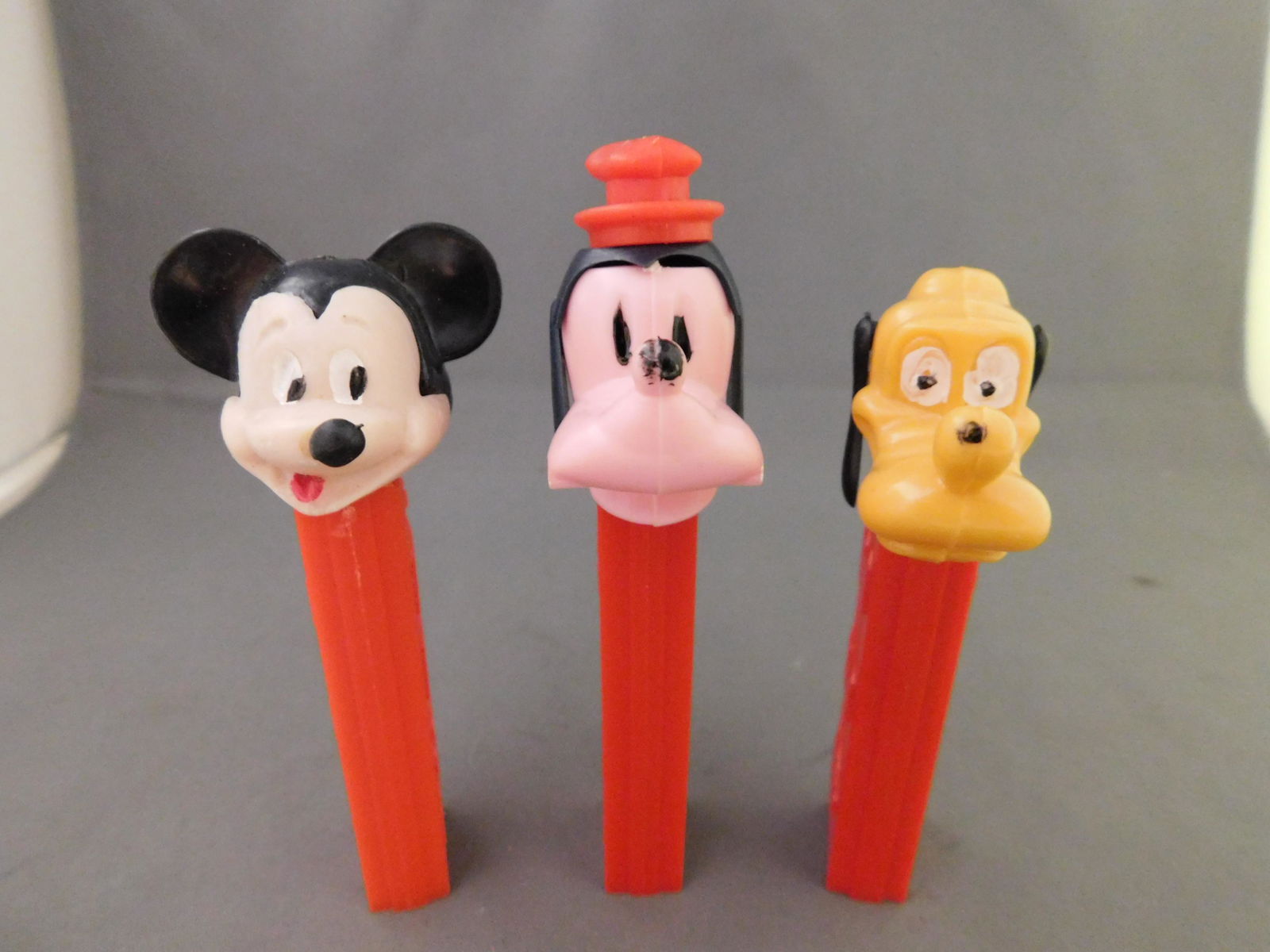 Disney Vintage Pez Lot of 3 - Mickey, Goofy, Pluto: Disney Vintage Pez Lot of 3. All have no feet. Included in this lot are Pluto and Goofy Made in Austria and Mickey with Red Body Made in Hong Kong. You are bidding at a live sale, please read the term