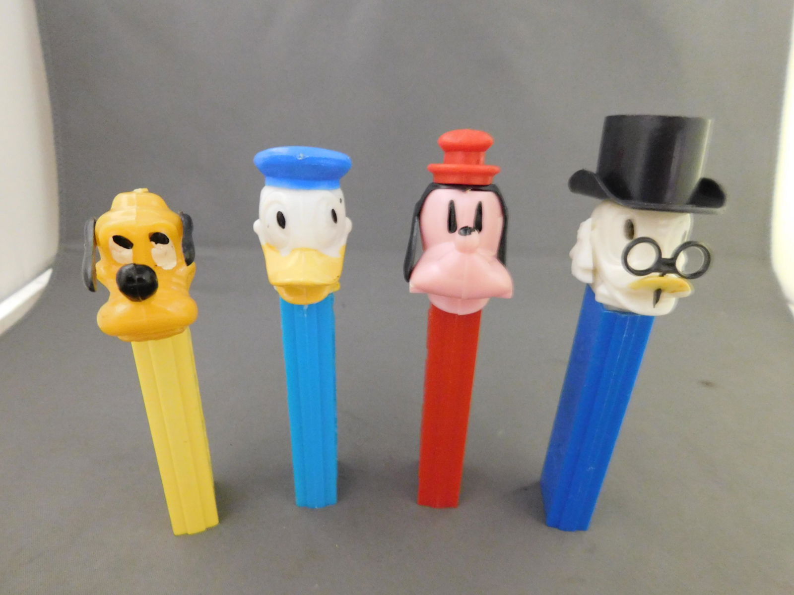 Disney Vintage Pez Lot of 4 - Scrooge, Donald, Goofy,: Disney Vintage Pez Lot of 4. All have no feet. Included in this lot are Scrooge and Donald Duck Made in Hong Kong, Goofy Made in Austria, and Pluto with Yellow Body Made in USA. You are bidding at a l