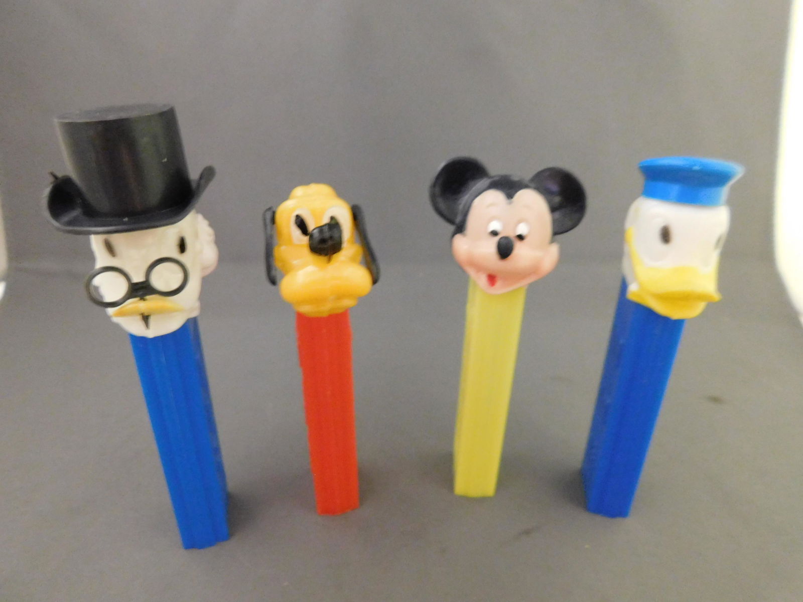 Disney Vintage Pez Lot of 4 - Scrooge, Donald, Pluto,: Disney Vintage Pez Lot of 4. They all have no feet. Included in this lot are Scrooge, Donald, and Pluto all made in Hong Kong and Mickey with Yellow Body made in Austria. You are bidding at a live sal