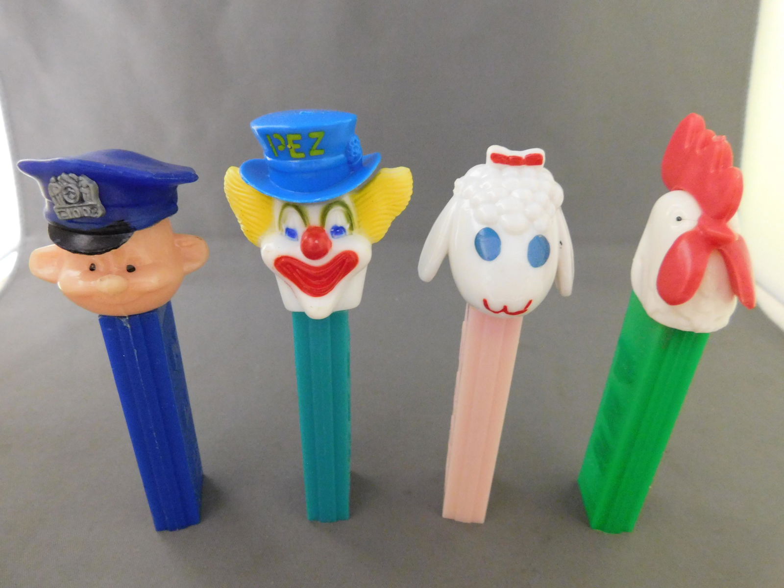 Mixed Vintage Pez Lot of 4: Mixed Vintage Pez Lot of 4. They all have no feet. Included in this lot are a Lamb, a Police Officer, and Peter the Clown all made in Hong Kong and Rooster with Green body and white head made in Austr