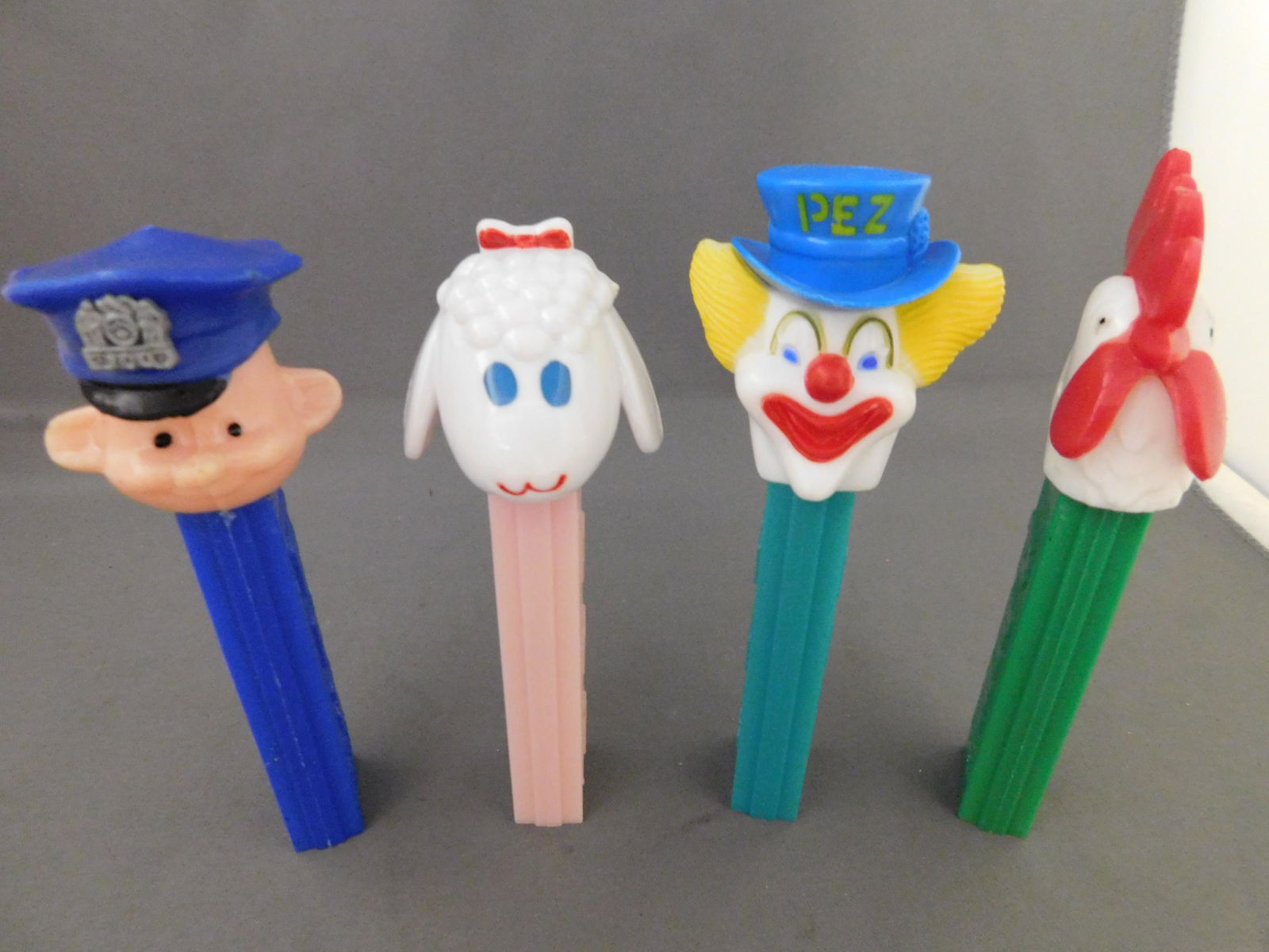 Mixed Vintage Pez Lot of 4: Mixed Vintage Pez Lot of 4. They all have no feet. Included in this lot are a Police Officer and Peter the Clown made in Hong Kong, a Rooster with Green body and white head made in Austria and a Lamb