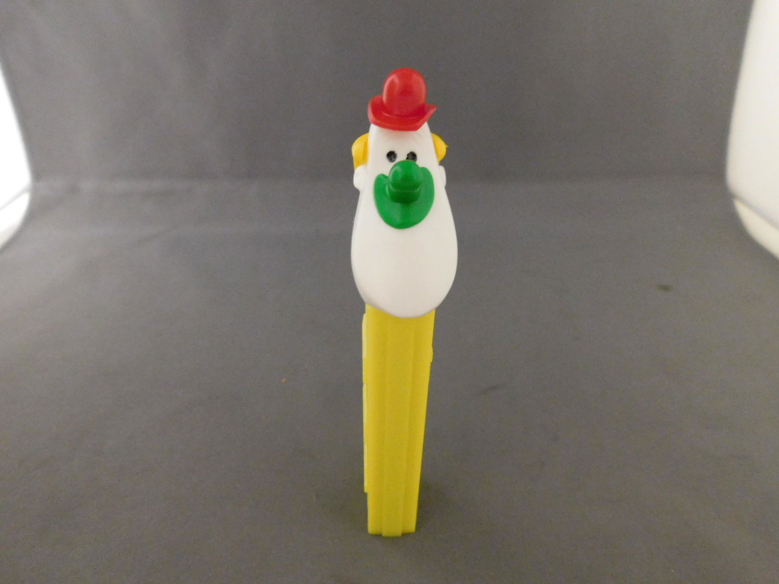 Vintage Long Face Clown Pez: Vintage Long Face Clown Pez. He has no feet. He has a yellow body with a green nose. Made in Austria. You are bidding at a live sale, please read the terms and conditions. We are offering contact-less