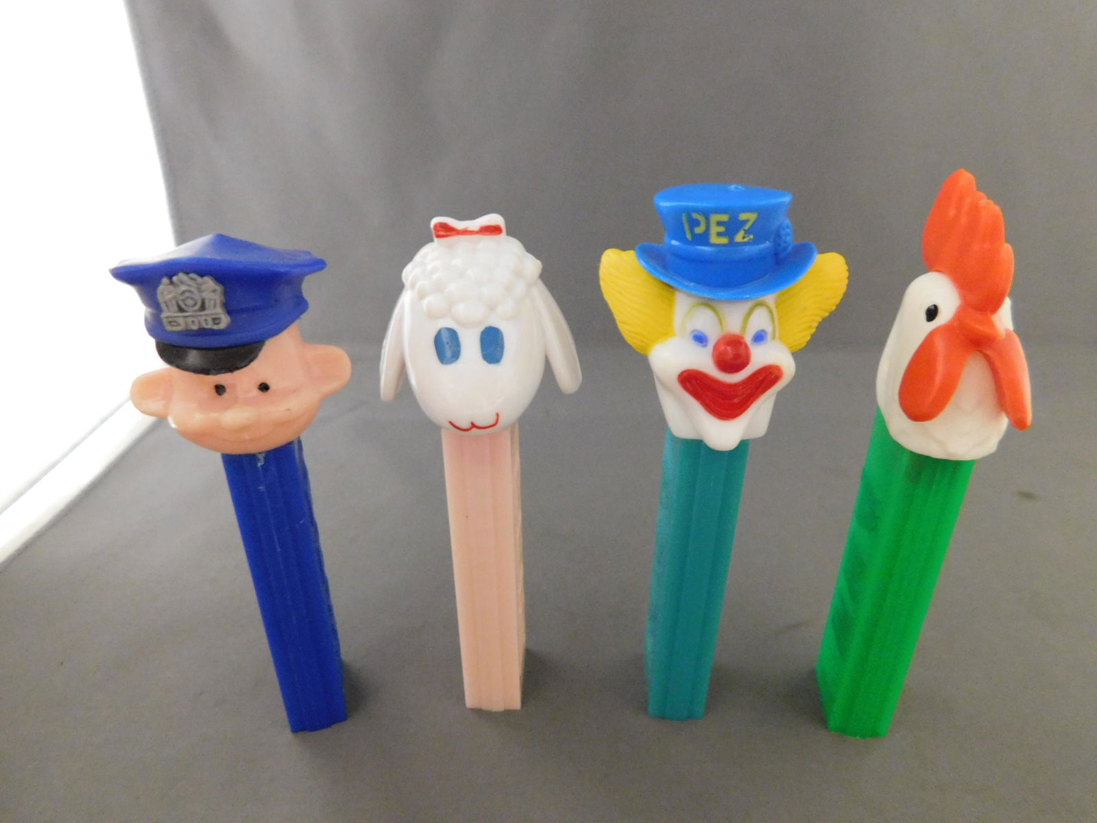 Mixed Vintage Pez Lot of 4: Mixed Vintage Pez Lot of 4. They all have no feet. Included in this lot are Peter the Clown and Police Officer made in Hong Kong, Rooster made in Austria, and Lamb made in Yugoslavia. You are bidding
