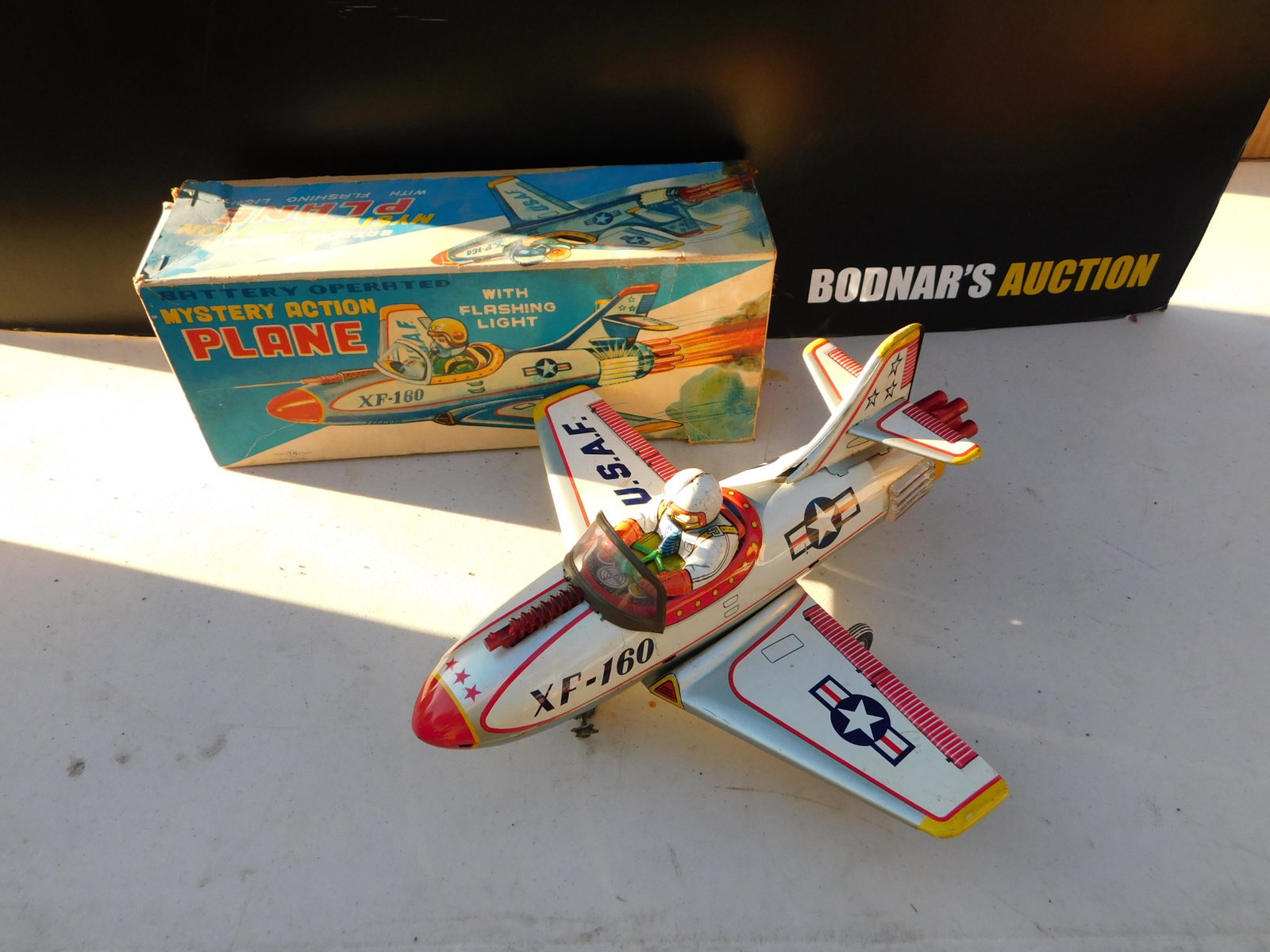 Japanese Tin Mystery Action Plane: Japanese Battery Operated Tin Mystery Action Plane with Flashing Light in Box. In very good to near mint condition. You are bidding at a live sale. Please read the terms and conditions. This sale will