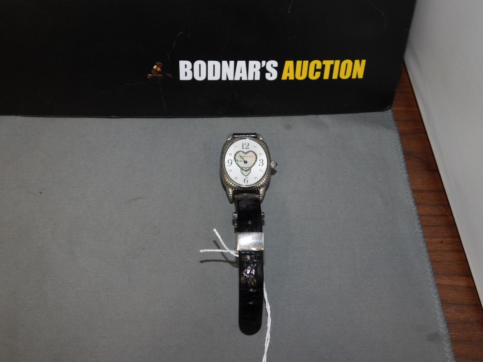 Judith Ripka Heart Watch: Judith Ripka stainless steel heart watch with black leather band. Inside measures 6". Band is adjustable. You are bidding at a live sale, please read the terms and conditions. We are offering contact-
