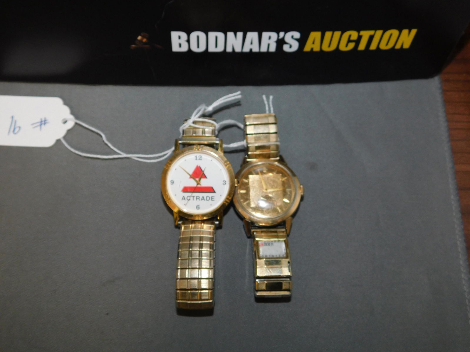 Movado Watch: Movado gold tone watch with stainless steel back. Stretch band. Scratches to the crystal and to the band. Also an Actrade gold tone watch.You are bidding at a live sale, please read the terms and cond