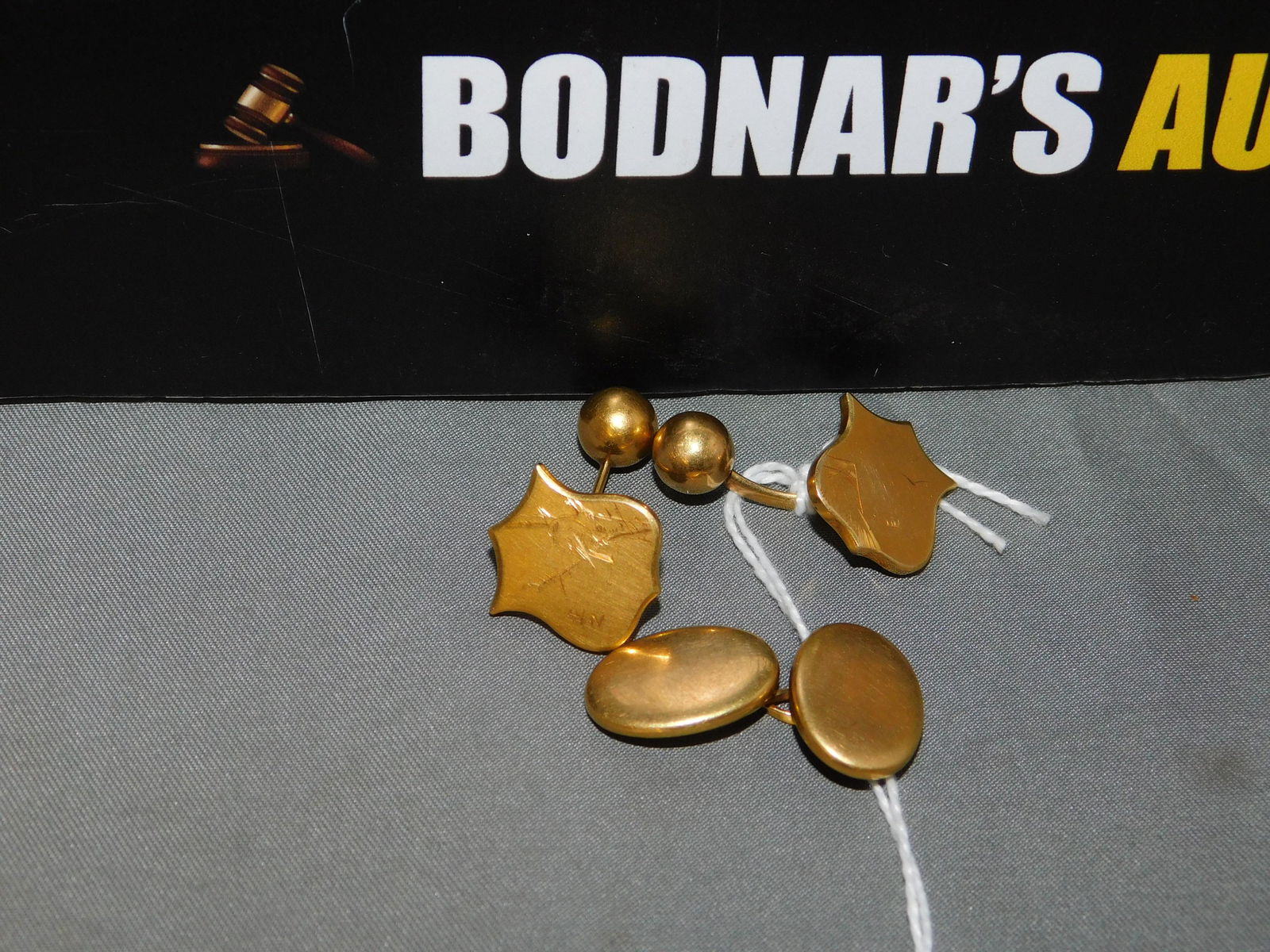 18K Cufflinks Etched Birds: 18K Oriental yellow gold shield cufflinks etched with birds. Shield measures 5/8" tall. Marked on the back. One cufflink was soldered and has some corrosion on back. You are bidding at a live sale, pl