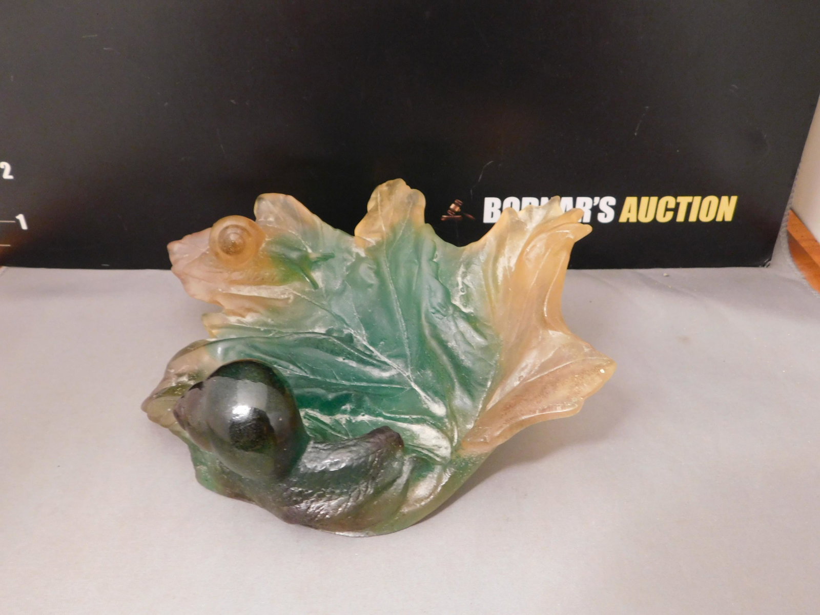 Daum France Leaf Bowl: Signed Daum France leaf bowl with snail shells in a green/orange matte glass. Measures approx. 2 1/2" tall x 7 1/2" wide. You are bidding at a live sale, please read the terms and conditions. We are o
