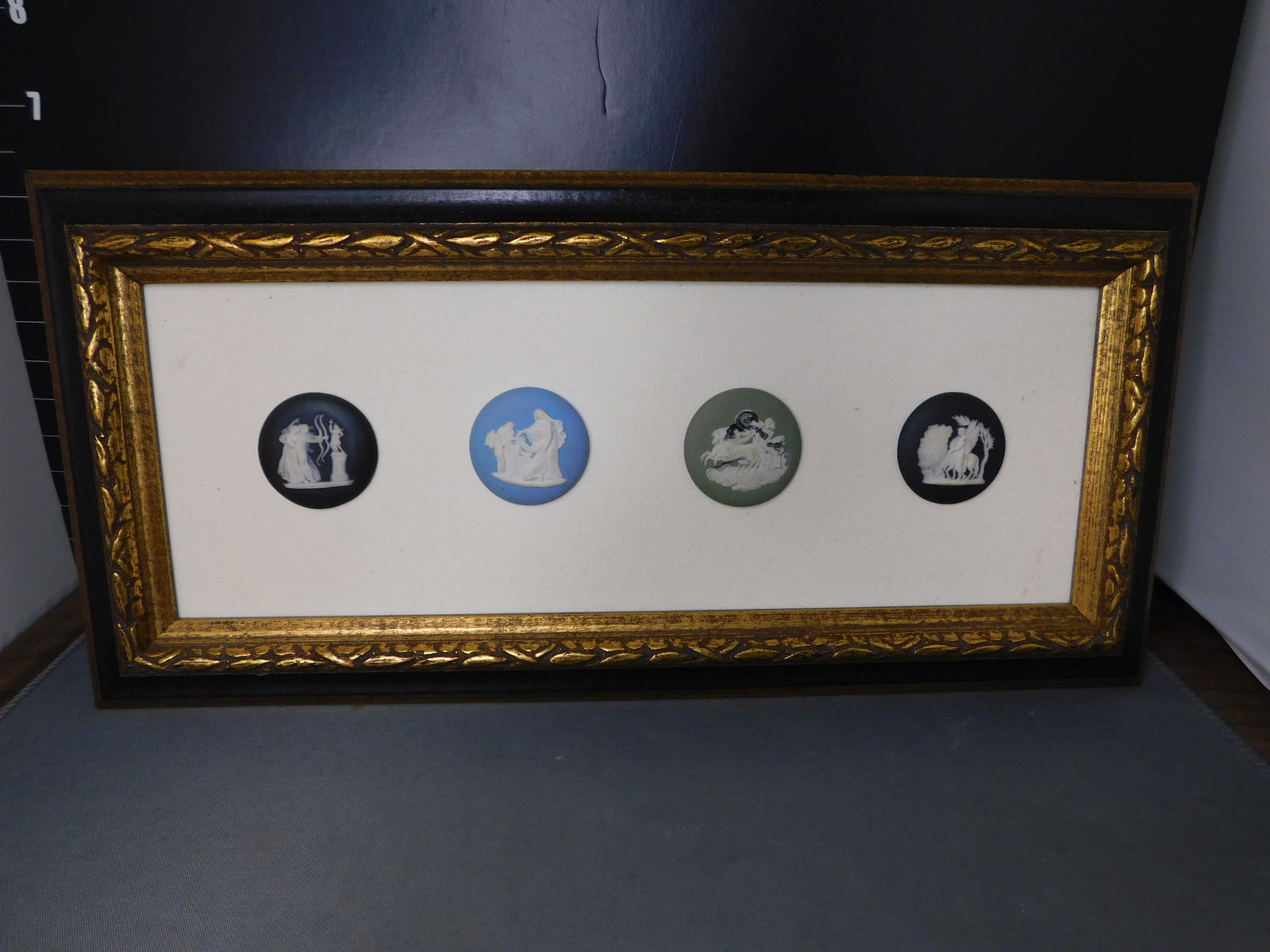 Framed Collage of 4 Wedgewood Jasperware Plaques: Framed Collage of 4 Wedgewood Jasperware Plaques. Measures 6.5" t x 13.5" long. You are bidding at a live sale, please read the terms and conditions. We are offering contact-less pick ups at our South