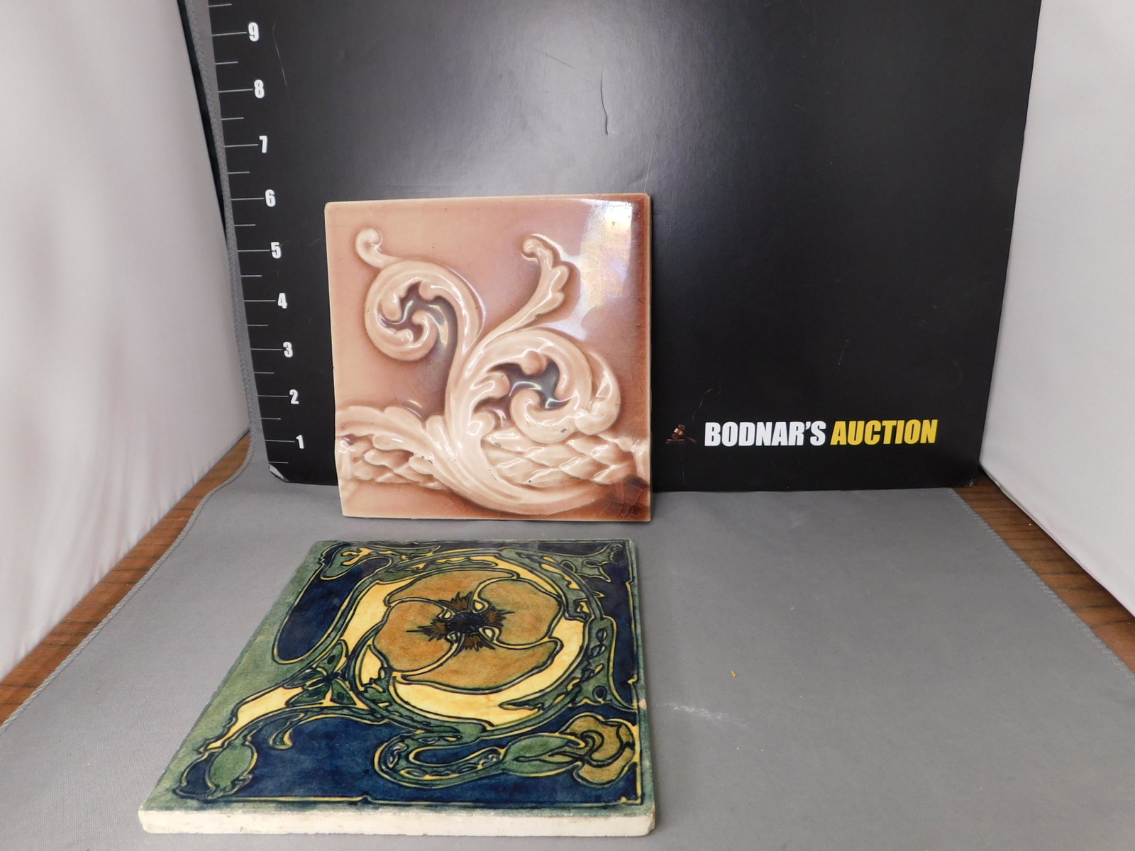 Lot of 2 Art Pottery Tiles: Lot of 2 Art Pottery Tiles. Brown Raised Relief Rococo Style - Measures 6" t x 6" w. Art Nouveau Flower measures 6" t x 6" w - European. You are bidding at a live sale, please read the terms and condi