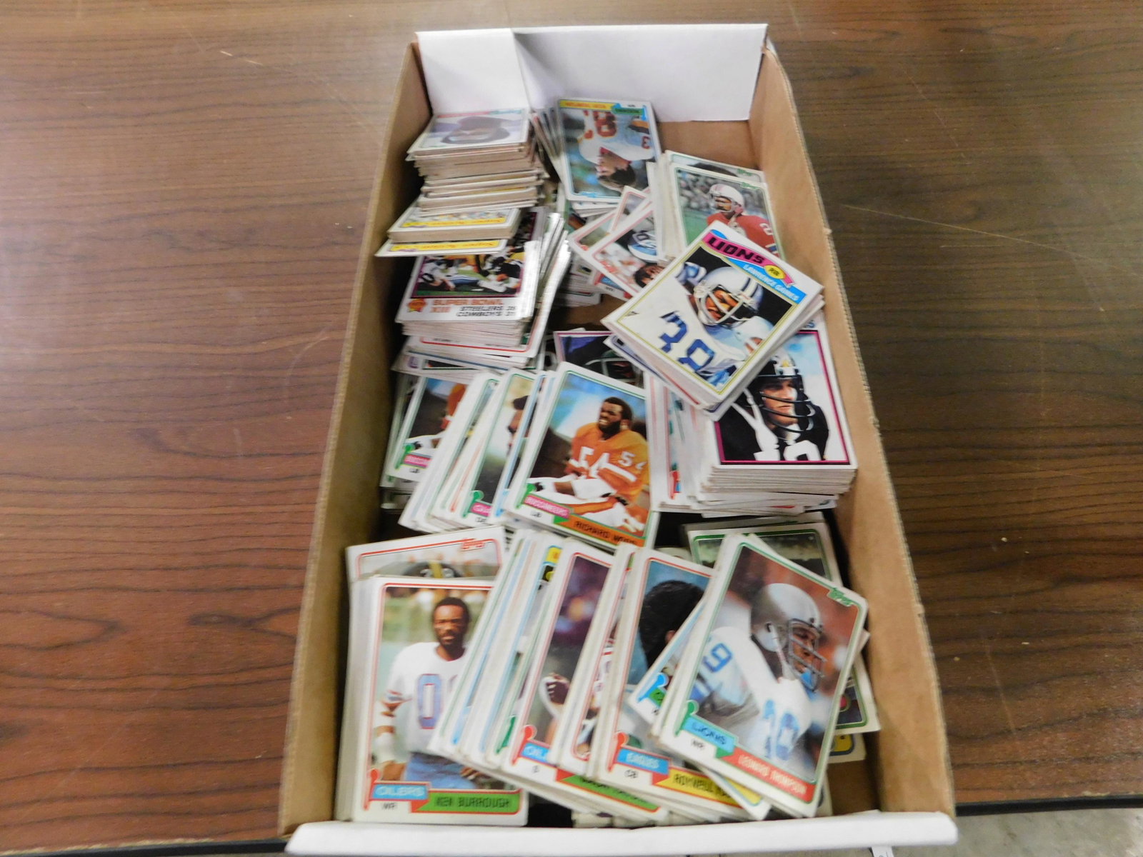 Box Lot of 80's Football Cards: Box Lot of 80's Football Cards. This sale will be broadcast live on sale day with an auctioneer and caller calling full descriptions of each lot being sold, as well as video feed of each lot. All item