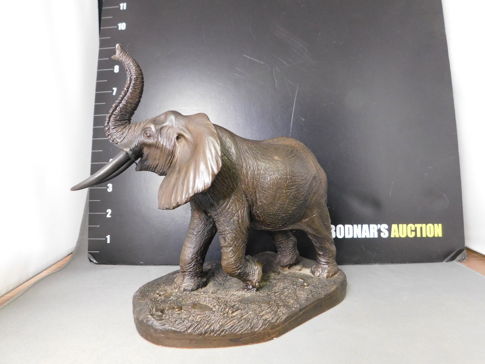Resin Elephant: Resin Elephant. Signed Tom Moukie. Label Heredits Limited Kirkby Stephen Westmoreland England. Measures 7" tall. This sale will be broadcast live on sale day with an auctioneer and caller calling full