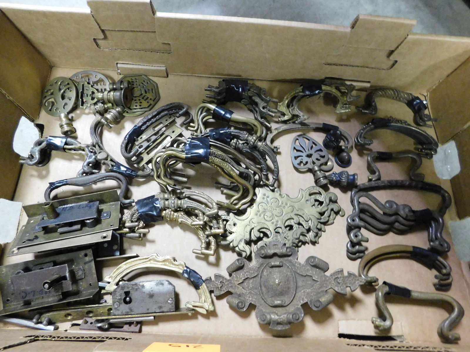 Box Lot of Brass Furniture Hardware: Box Lot with Brass Furniture Hardware. This sale will be broadcast live on sale day with an auctioneer and caller calling full descriptions of each lot being sold, as well as video feed of each lot. A