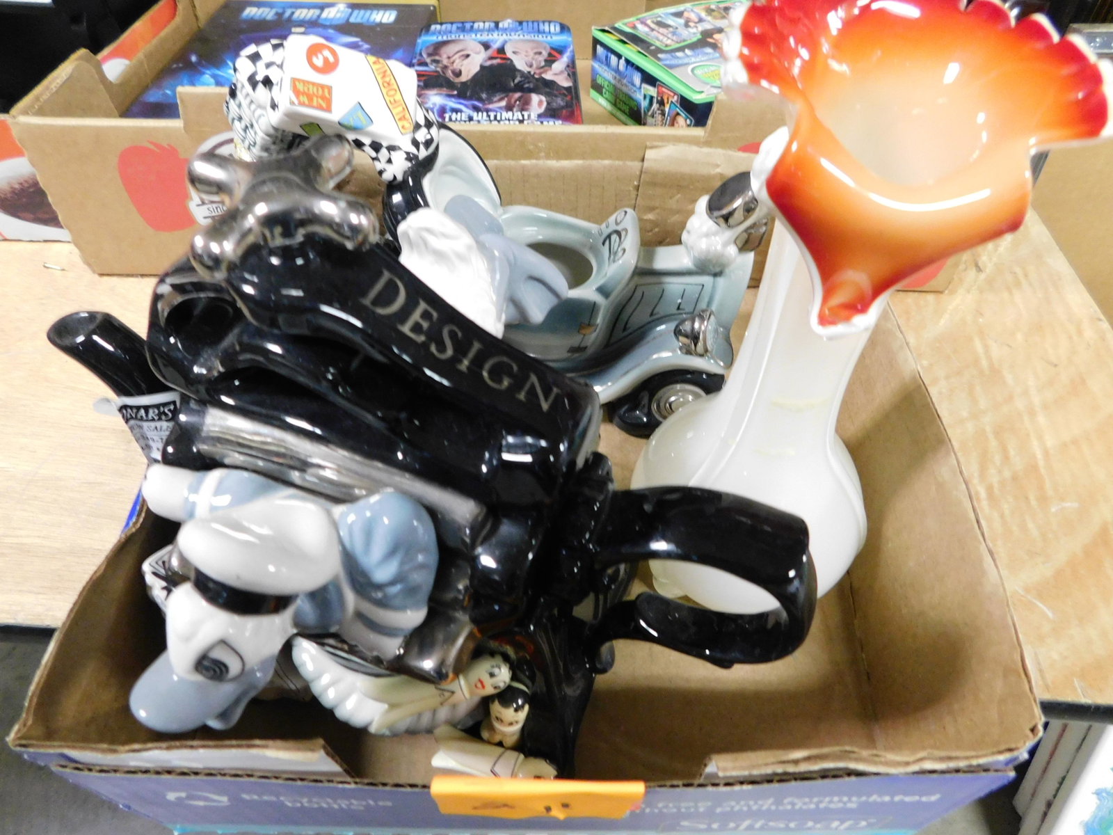 Box Lot of As-Is Disney and Art Glass: Box Lot of As-Is Disney Teapots and Art Glass Vase. This sale will be broadcast live on sale day with an auctioneer and caller calling full descriptions of each lot being sold, as well as video feed o