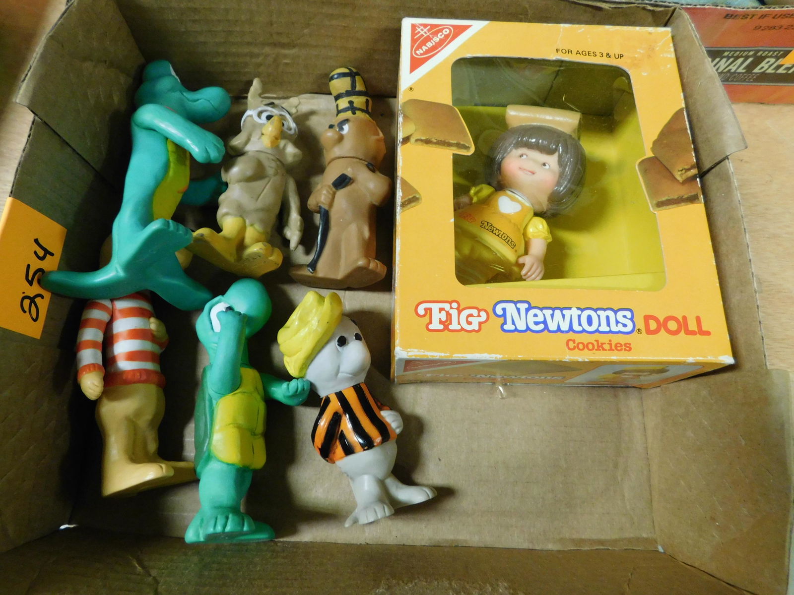 Box Lot with Walt Kelly Figures and Fig Newton Doll: Box Lot with Walt Kelly Figures and Fig Newton Doll. This sale will be broadcast live on sale day with an auctioneer and caller calling full descriptions of each lot being sold, as well as video feed