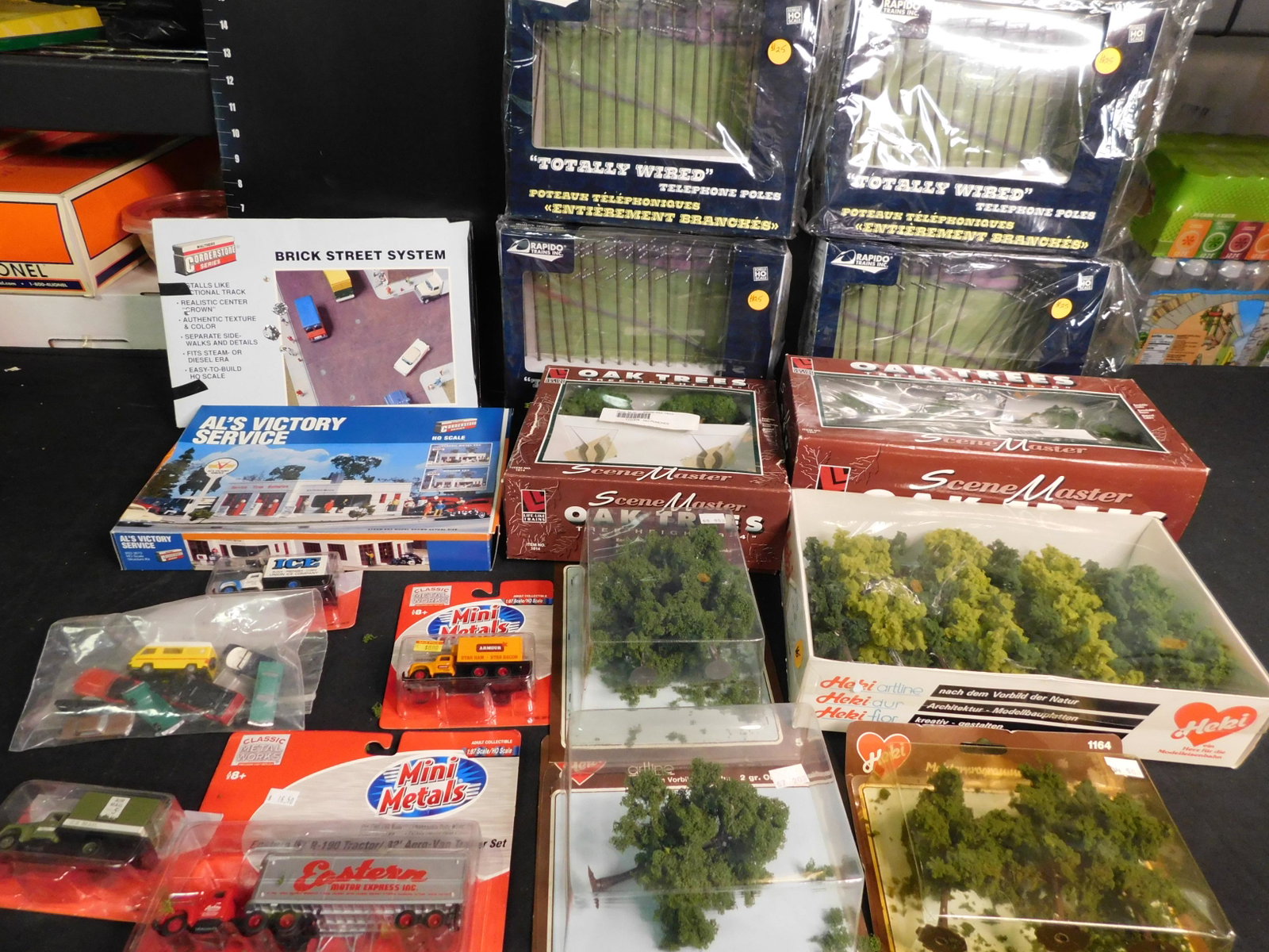 Large Lot of Train Accessories: Large Lot of Train Accessories including 4 Boxes of Sealed Telephone Poles, Sealed Boxes of Trees, Foliage, Mini Cars and More. You are bidding at a live sale, please read the terms and conditions. We