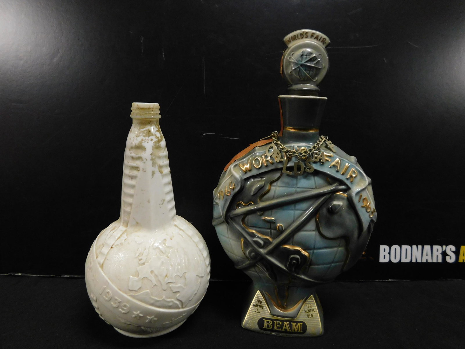 Lot of 2 World's Fair Decanters: Lot of 2 World's Fair Decanters. One is from 1939 and the Jim Beam is from 1964. 1939 is missing the top. This sale will be broadcast live on sale day with an auctioneer and caller calling full descri