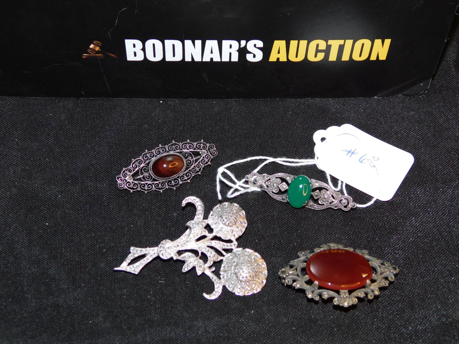Lot of 4 Silver Pins: Lot of silver pins. Pin with cabochon stone and filigree is marked "800". Other pins are sterling and have marcasite accents. Marked on the back. Measures approx. 1 3/4"-2 1/4". You are bidding at a l