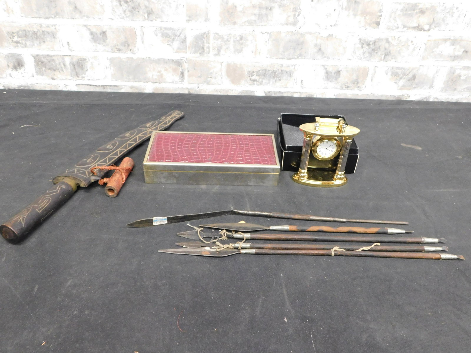 Lot with Brass Quartz Clock and Tribal Souvenirs: Lot with Brass Quartz Clock and Tribal Souvenirs. This sale will be broadcast live on sale day with an auctioneer and caller calling full descriptions of each lot being sold, as well as video feed of 