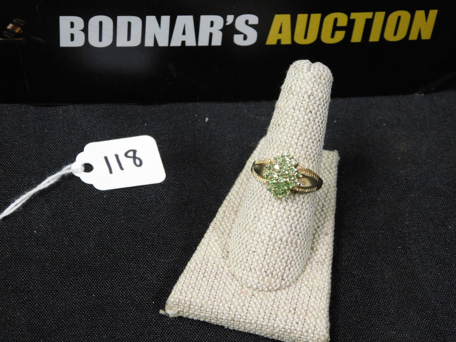 10K Women's Ring: 10K women's ring with green stones, possibly peridot. Marked. Size 8. All invoices must be paid within 24 hours of the sale. All items are shipped USPS and will be billed separately. A $10 handling fe