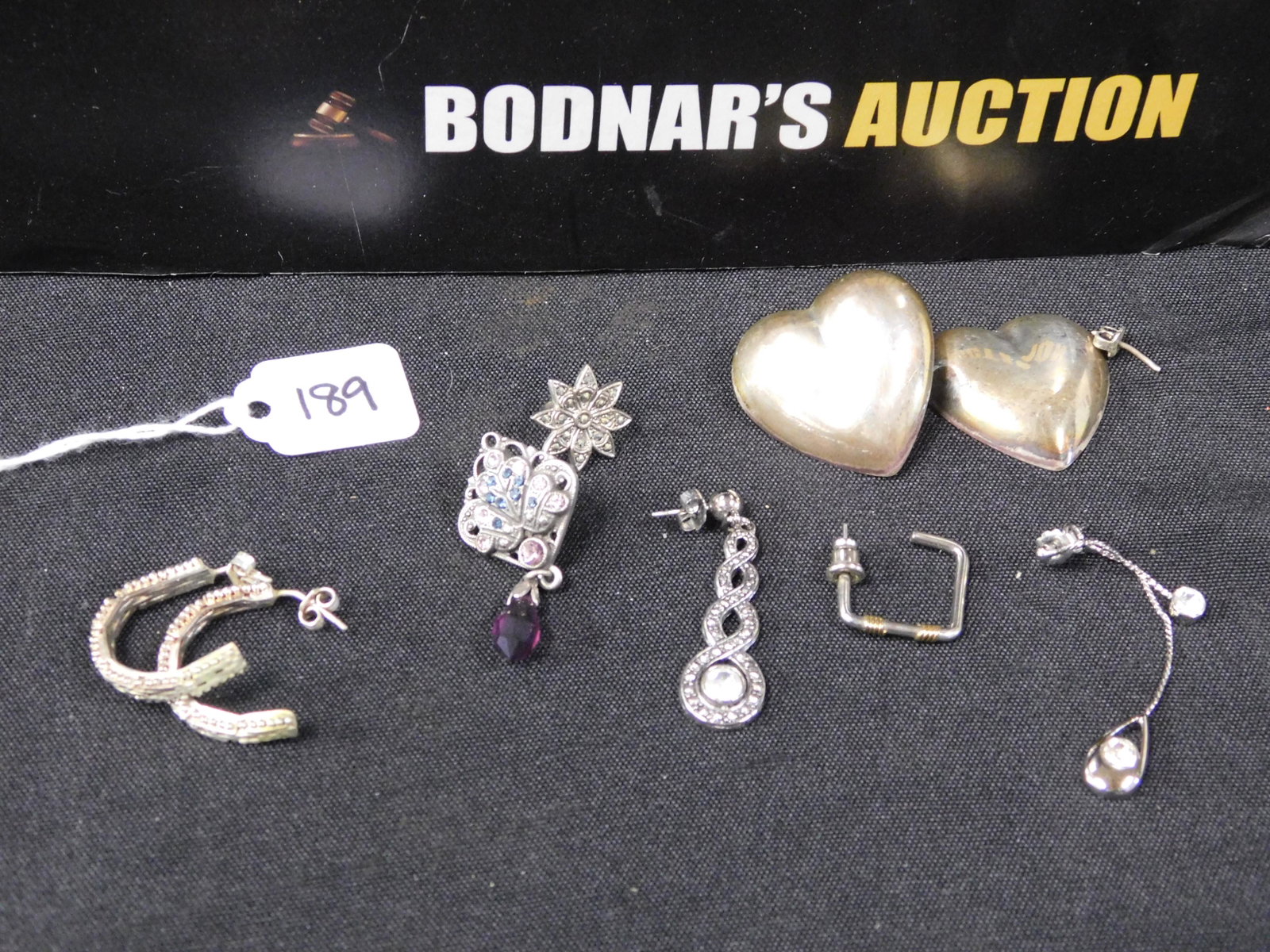 Sterling Silver Lot: Sterling silver scrap lot including a pair of puffy heart earrings - one with a broken post, a pair of partial hoops - one is slightly bent, and odd earrings. All invoices must be paid within 24 hours