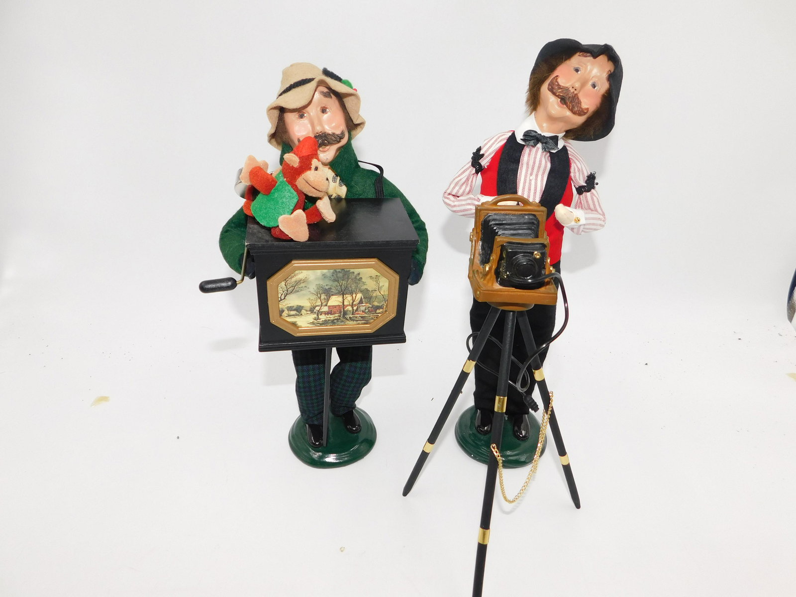 Lot of 2 Byers Choice Carolers: Byers Choice Caroler Lot of 2 including Photographer and Organ Grinder. Both are signed on base. Please read the terms and conditions. This sale will be broadcast live on sale day with full descriptio