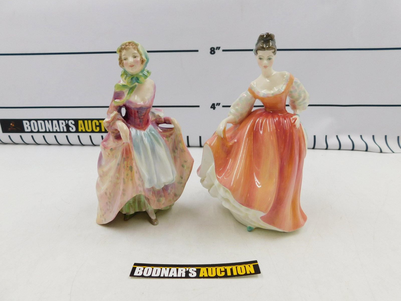 Lot of 2 Royal Doulton Figurines: Lot of 2 Royal Doulton Figurines. Including "Suzette" HN 2026 and "Fair Lady (Coral Pink)" HN 2835. Measures approx. 7.25" - 7.75" tall. All invoices must be paid within 24 hours of the sale. If you n