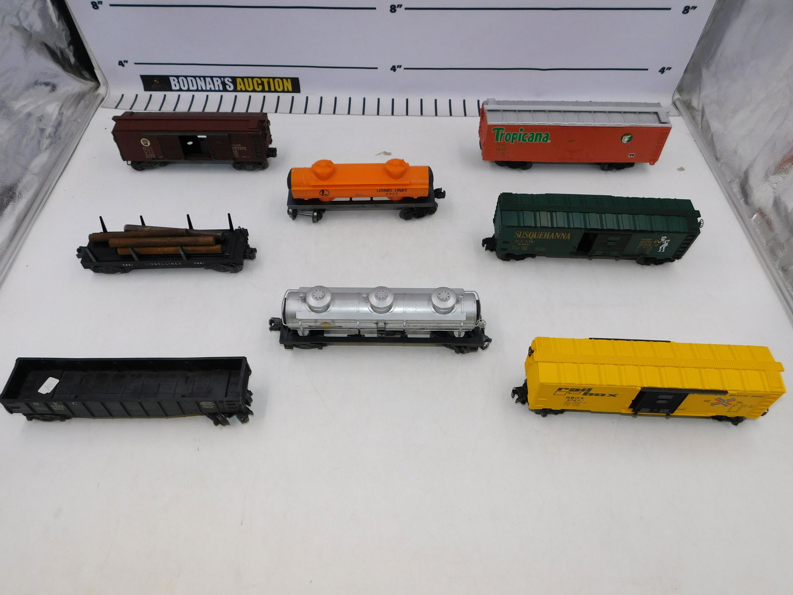 Lot of Lionel O Gauge Rolling Stock: Lot of Lionel O Gauge Rolling Stock including Tropicana Boxcar 1247, Susquehanna Boxcar 9402, Railbox Boxcar 9467, Postwar NYC Gondola 6462 Black, Postwar PRR Automobile Boxcar X2758, Log Dump Car 346