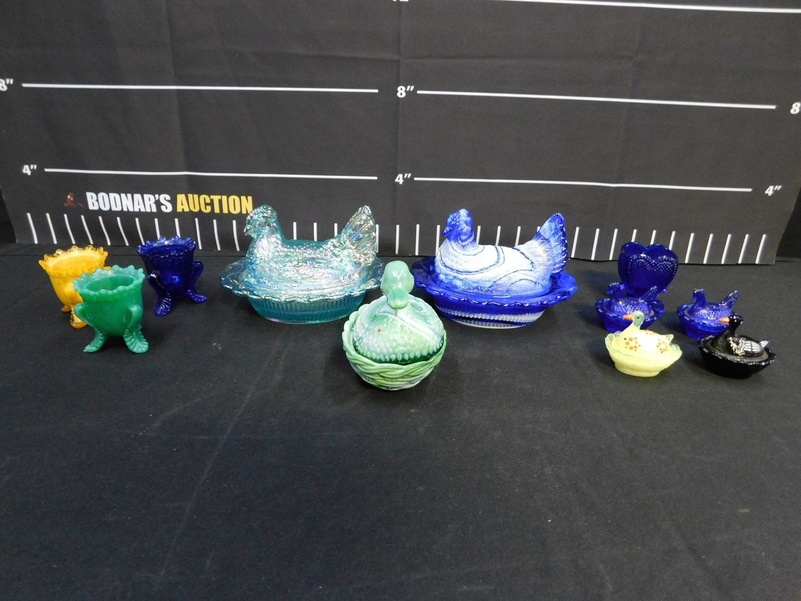 Lot of Glass and Slag Glass Collectibles: Lot of Glass and Slag Glass Hens on a Nest, Egg Cups, and More. The largest measures 6.5" long x 4.5" tall. All invoices must be paid within 24 hours of the sale. This auction is Local Pick Up, Shippi