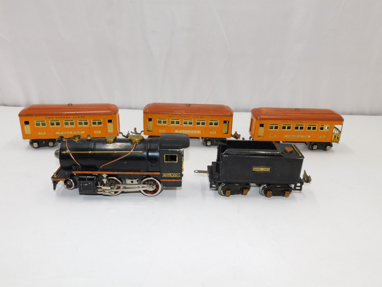 Lionel Pre War O Gauge Train Set: Lionel O Gauge Train Set including #258 Pre War 2-4-O Black Steam Engine with Tender, (2) #603 Orange Passenger Cars, and #604 Observation Car. Cars have discoloration to roofs. One of the 603 Cars is