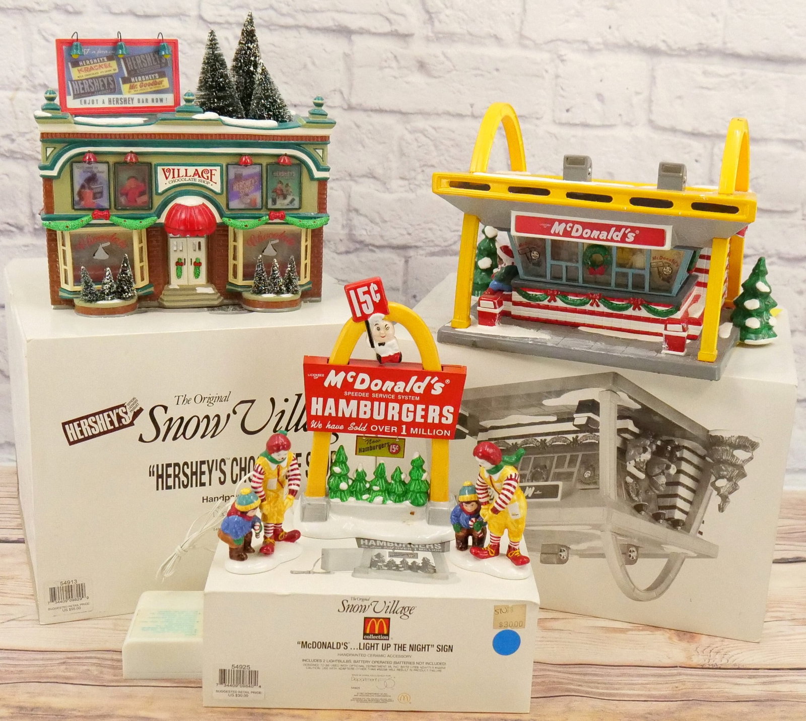 Lot of Department 56 Snow Village Houses and Accessories: Lot of Department 56 Snow Village Houses and Accessories including Hershey's Chocolate Shop - Some chipping on Base and McDonald's - Strip on Top Edge is Loose and Minor chipping on base - Comes with 
