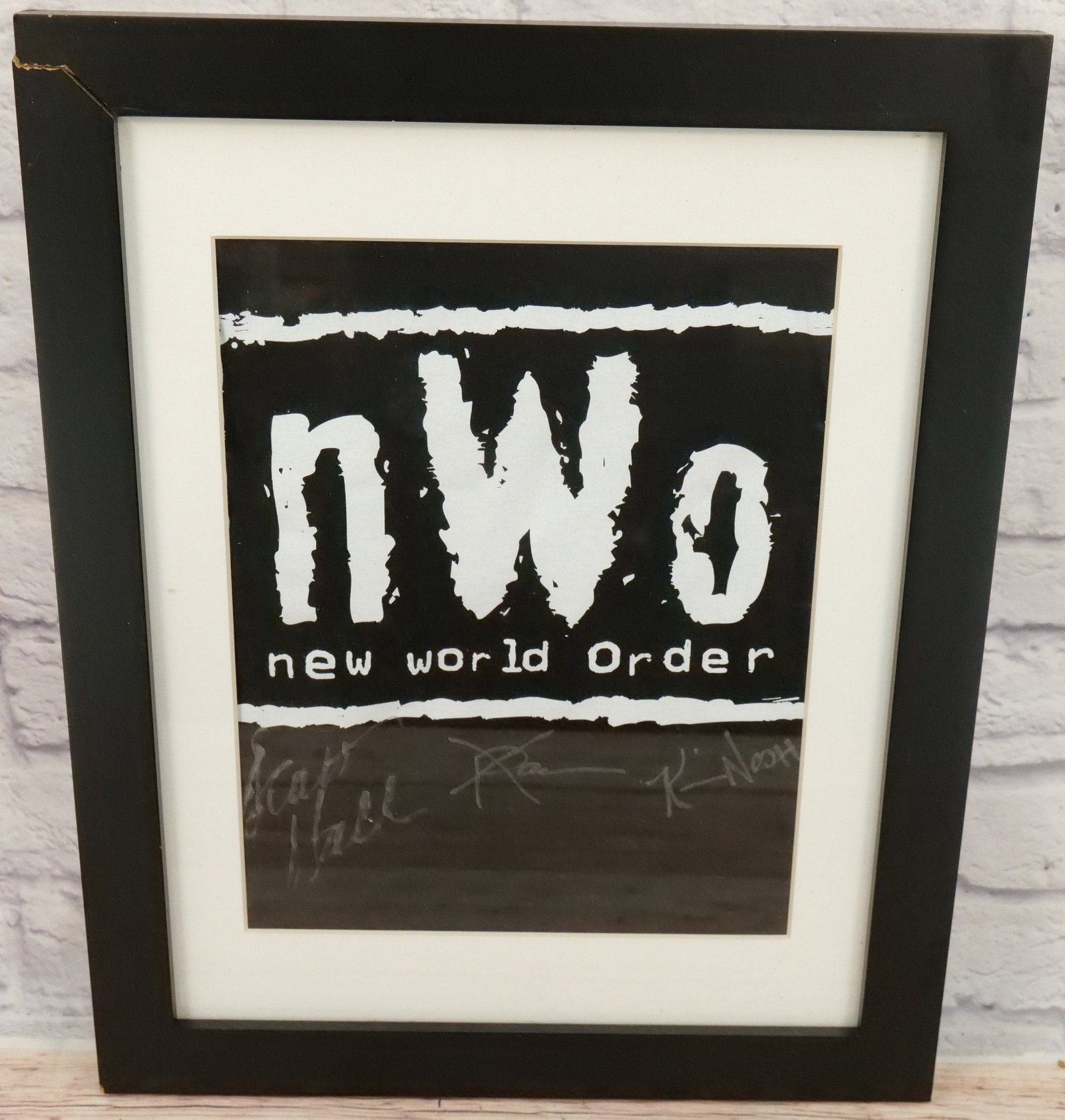 NWO Triple Signed T-Shirt: Framed NWO Autographed T-Shirt including Signatures by Scott Hall, Kevin Nash and "Syxx" Sean Waltman. Frame measures 20.5" tall x 16.75" wide. This autograph comes with a 30 day guarantee. It came fr