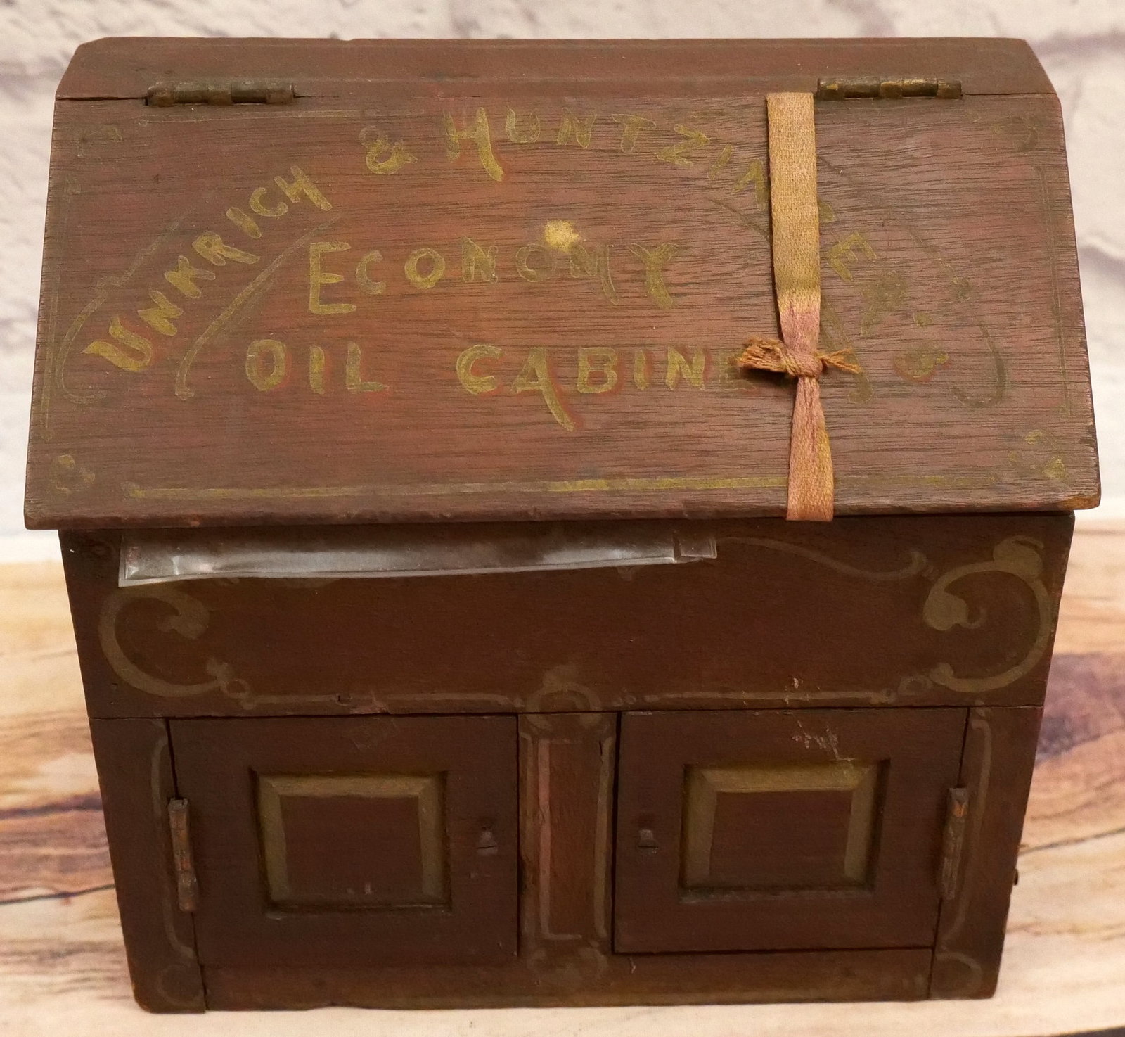 Miniature Wooden Cabinet: Miniature Wooden Cabinet. Marked with paint decoration Unkrich & Huntzinger's Economy Oil Cabinet. Has paint decoration interior and exterior. Has original paper label attached. Marked 1876. Measures 