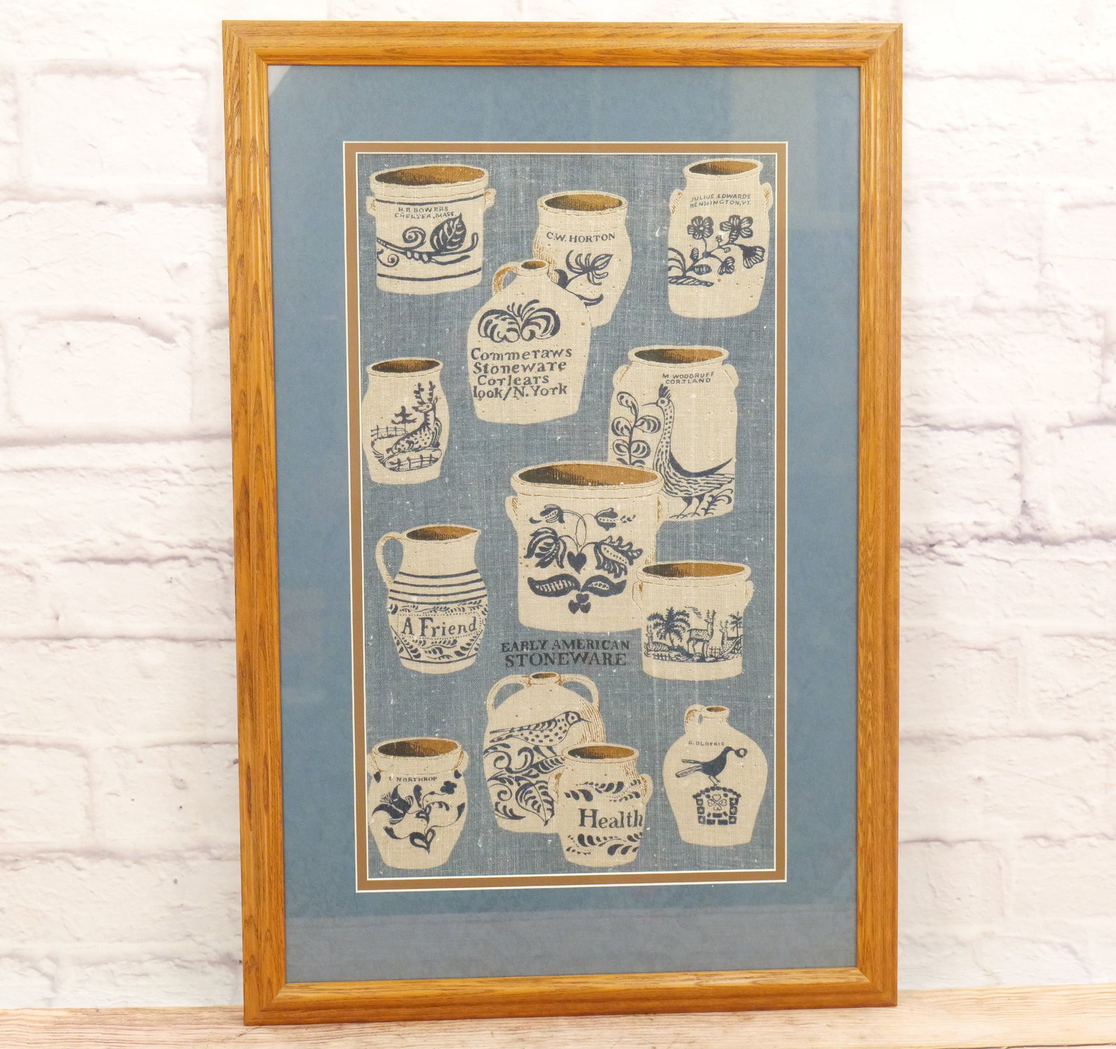 Framed Embroidery of Stoneware Crocks: Framed Embroidery of stoneware crocks, entitled Early American Stoneware including CW Horton, Julis Edwards Bennington VT, M Woodruff Corjland and others, measures 35 inches tall by 23 inches wide. Al