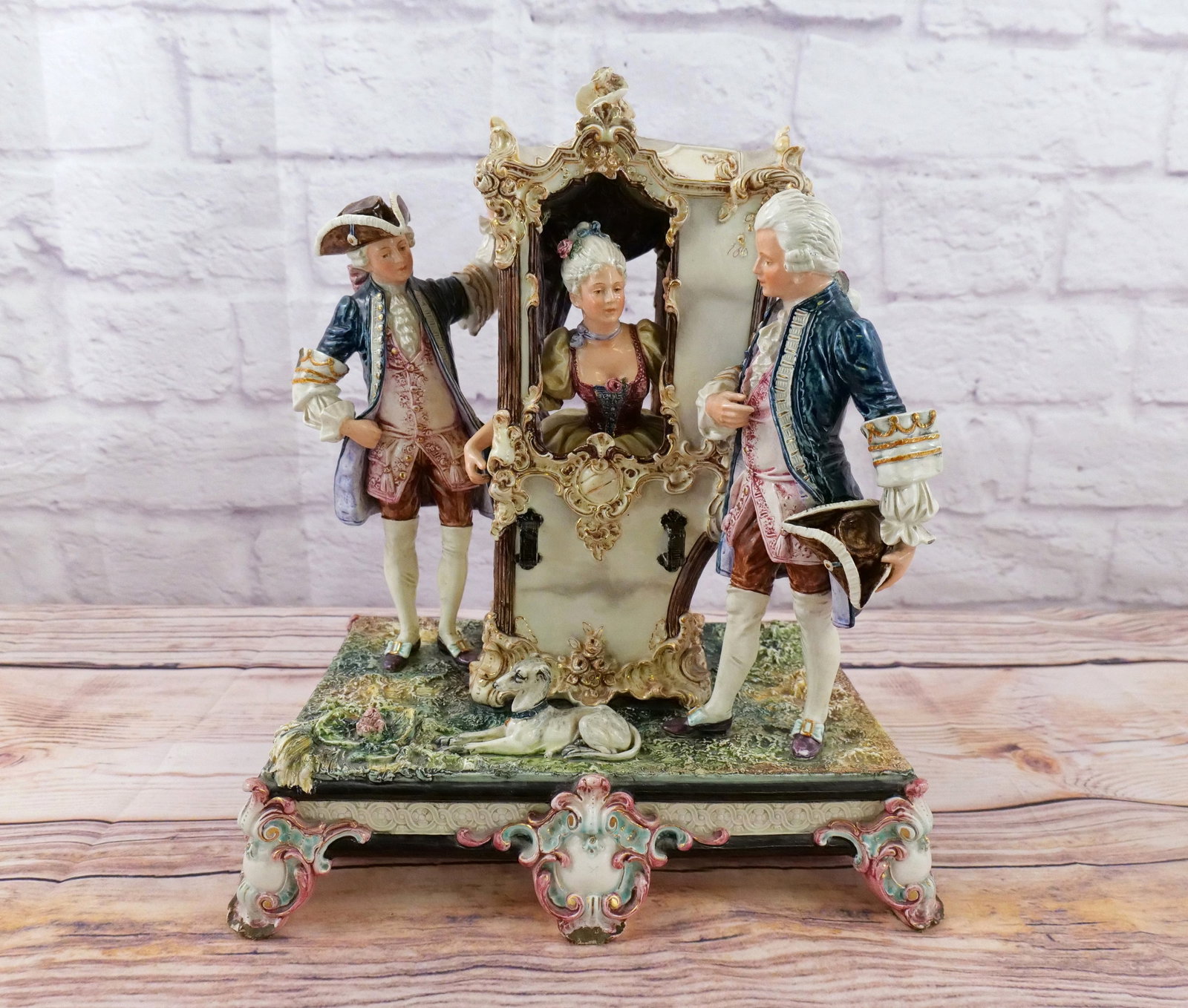 19th Century Porcelain/Pottery Grouping: 19th Century Porcelain/Pottery grouping depicting a French 18th century Sedan (Carrying Box) with woman and men. Has chipping on base and some of the edges of the men's arms. Base has a old repair and