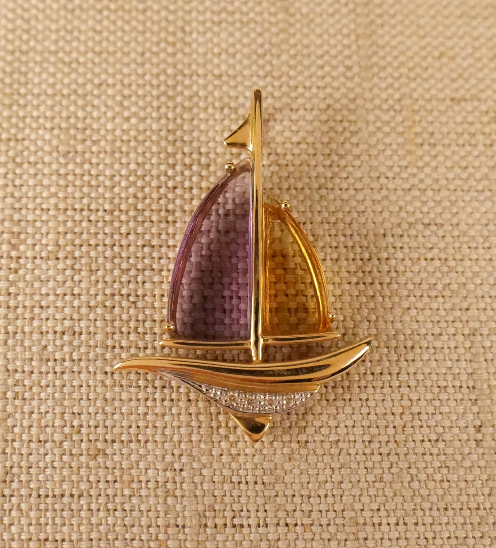 14K Yellow Gold Sail Boat Pendant with Gemstones: 14K Yellow Gold Sail Boat Pendant with Gemstones. 14k yellow gold sail boat pendant featuring sails set with prong set triangular amethyst and citrine cabochons with a grid like facet and 4 round cut