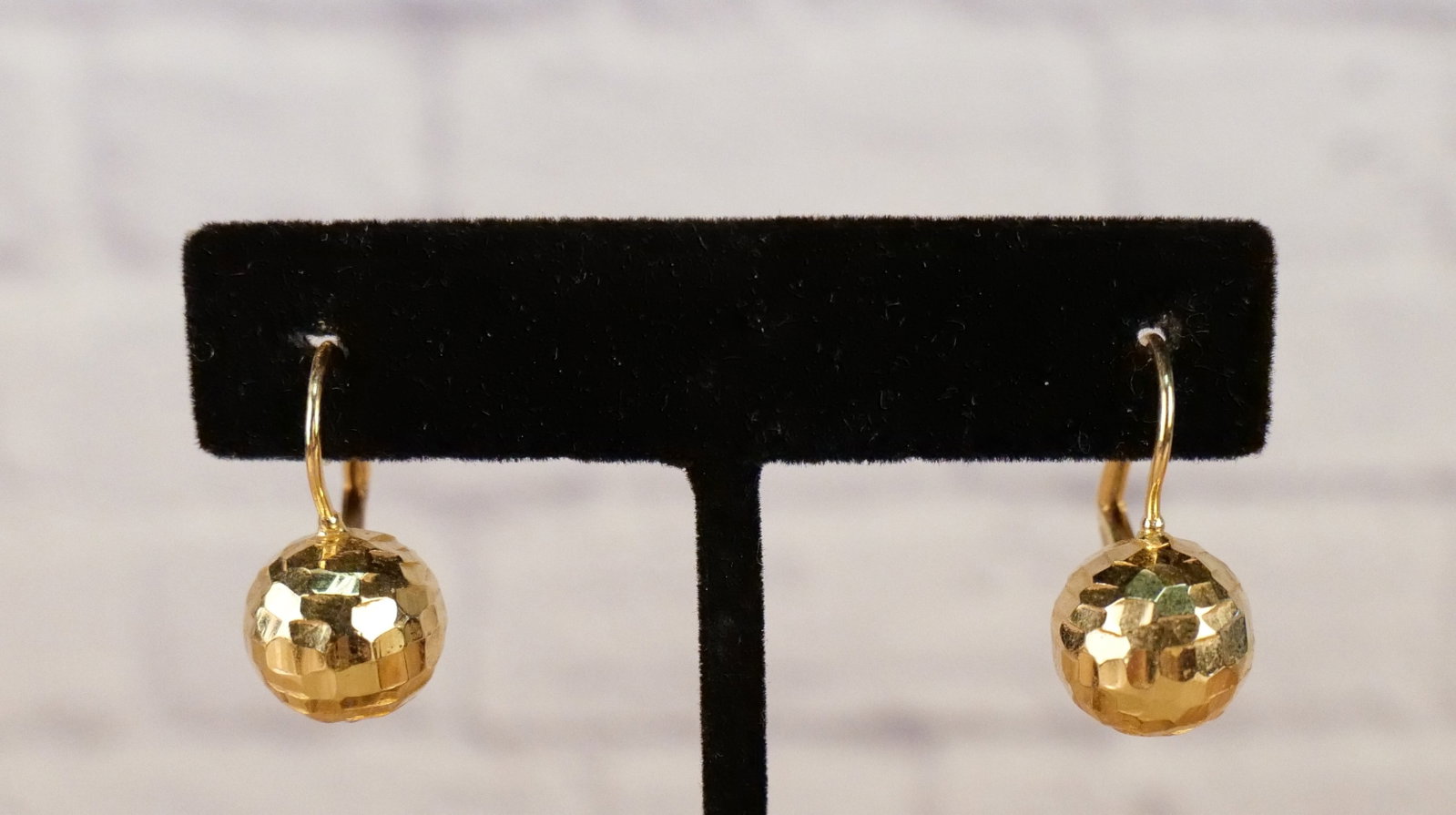 Faceted 14K Yellow Gold Ball Earrings: Faceted 14K Yellow Gold Ball Earrings. 14k yellow gold earrings featuring attached hollow faceted gold balls with hook posts and hinged lever backs. The earrings measure .89'' long by .45'' wide and t