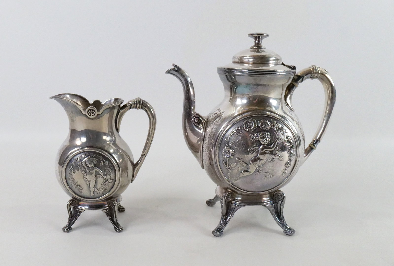 Reed & Barton Silverplate Teapot and Creamer: Reed & Barton Silverplate Teapot and Creamer. Has beautiful Cherub design with Eastlake Victoria Foot. Signed Reed & Barton 2810. Creamer is tipsy. Measures 10" tall. All invoices must be paid within 