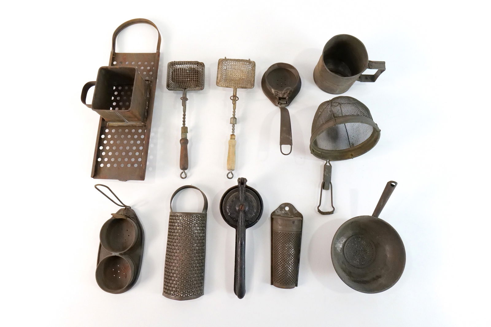 Lot of Kitchen Primitives: Lot of Kitchen Primitives including Egg Poachers, Lemon Squeezer, Milk Strainer, Flour Sifter, Soap Savers, Half Round Graters, and Cheese Grater. Largest measures 14.5" long. All invoices must be pai