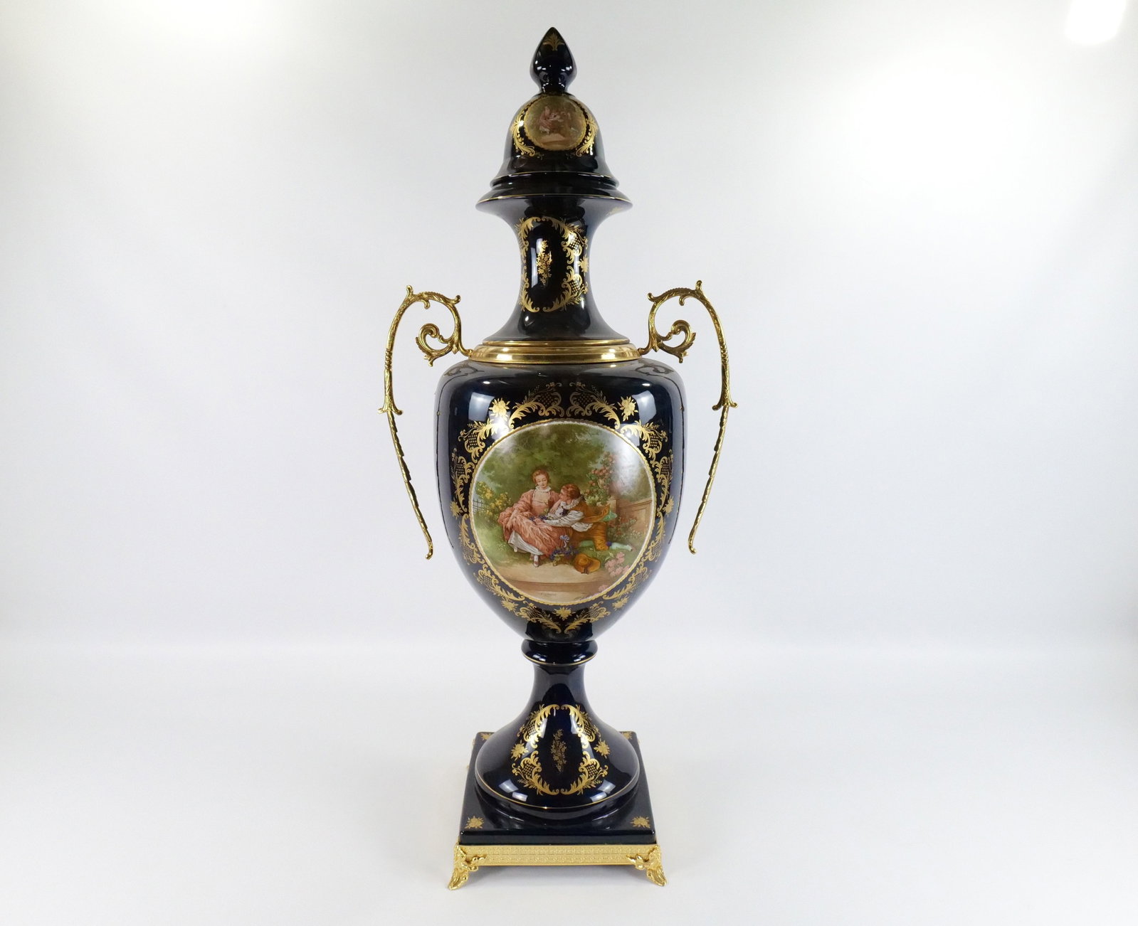 Monumental Limoges Style Covered Urn: Monumental Limoges Style Covered Urn. Hand Painted and Transferware. Cobalt Blue with Brass Accents. Depicting a boy courting a girl. Good Condition. Measures 45" tall x 20" diameter. All invoices mus