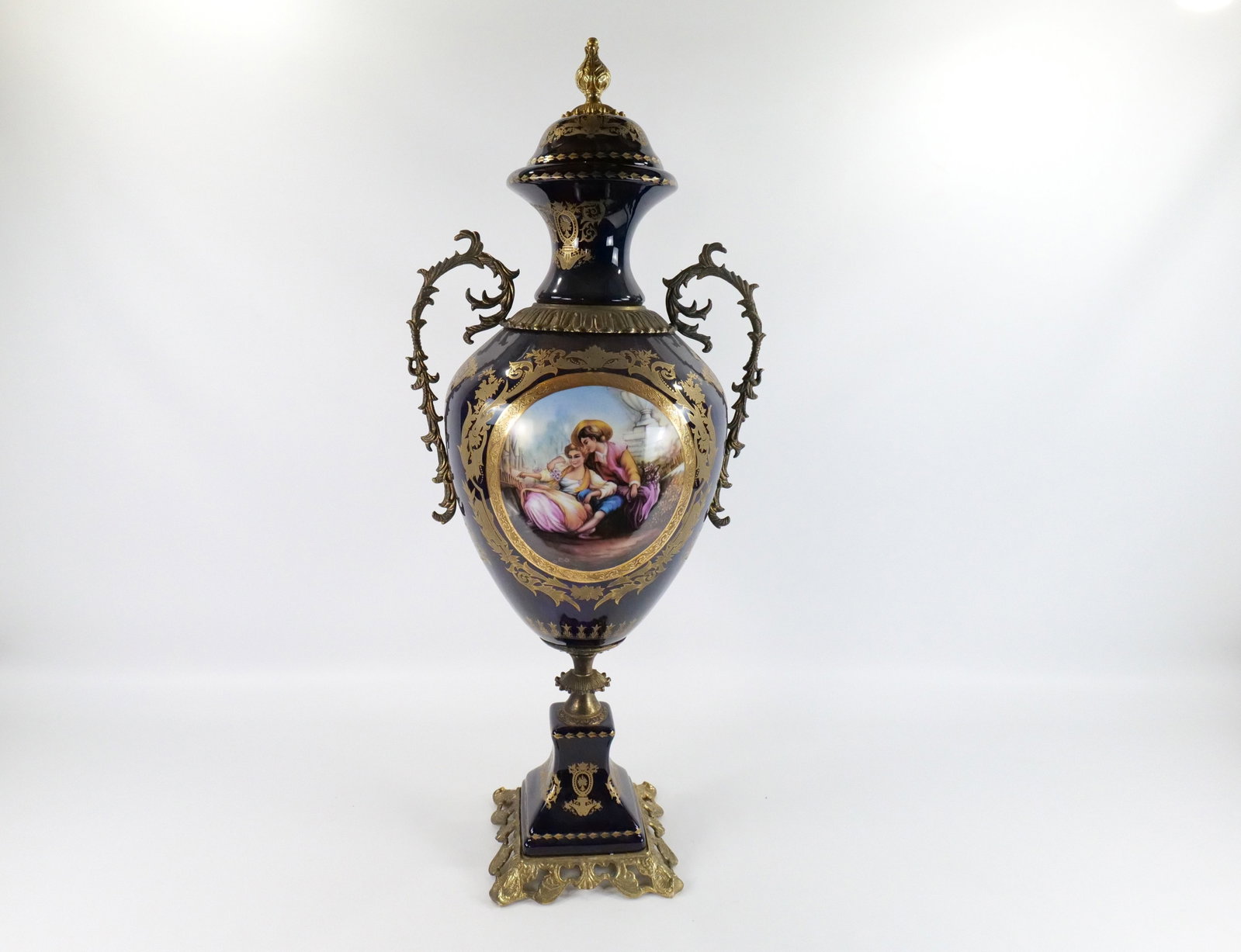 Monumental Limoges Style Covered Urn: Monumental Limoges Style Covered Urn. Hand Painted and Transferware. Cobalt Blue with Brass Accents. Depicting a boy courting a girl. Matches Lot #132. Good condition. Measures 43" tall x 19" diameter