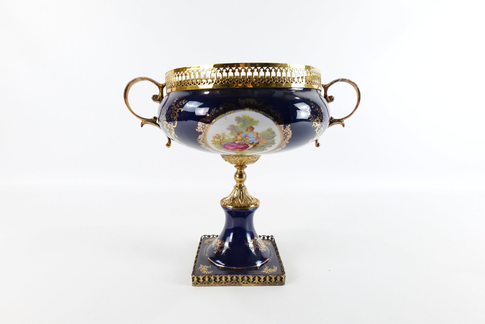 Limoges Style Porcelain Centerpiece: Limoges Style Hand Painted with Transferware Porcelain Centerpiece. Cobalt Blue with Brass Mounts. Top metal rim has a repair. Top also is a little crooked. Signed Fine Decorative Porcelain. Measures 