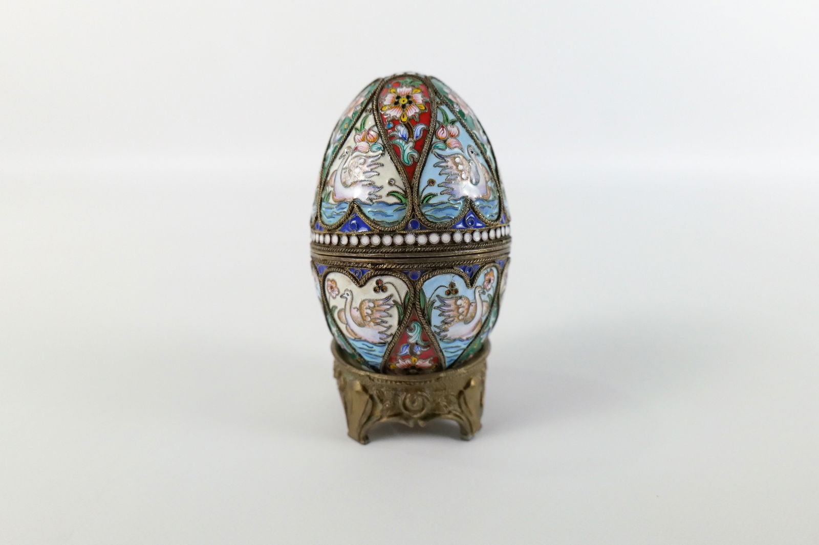 Russian Silver and Enamel Faberge Style Decorative Egg Box: Russian Silver and Enamel Faberge Style Decorative Egg Box. Swan and Flower Decoration. Has gold wash on the interior. Unmarked. Comes with Stand - Not original to egg. Measures 3" tall x 2.25" diamet