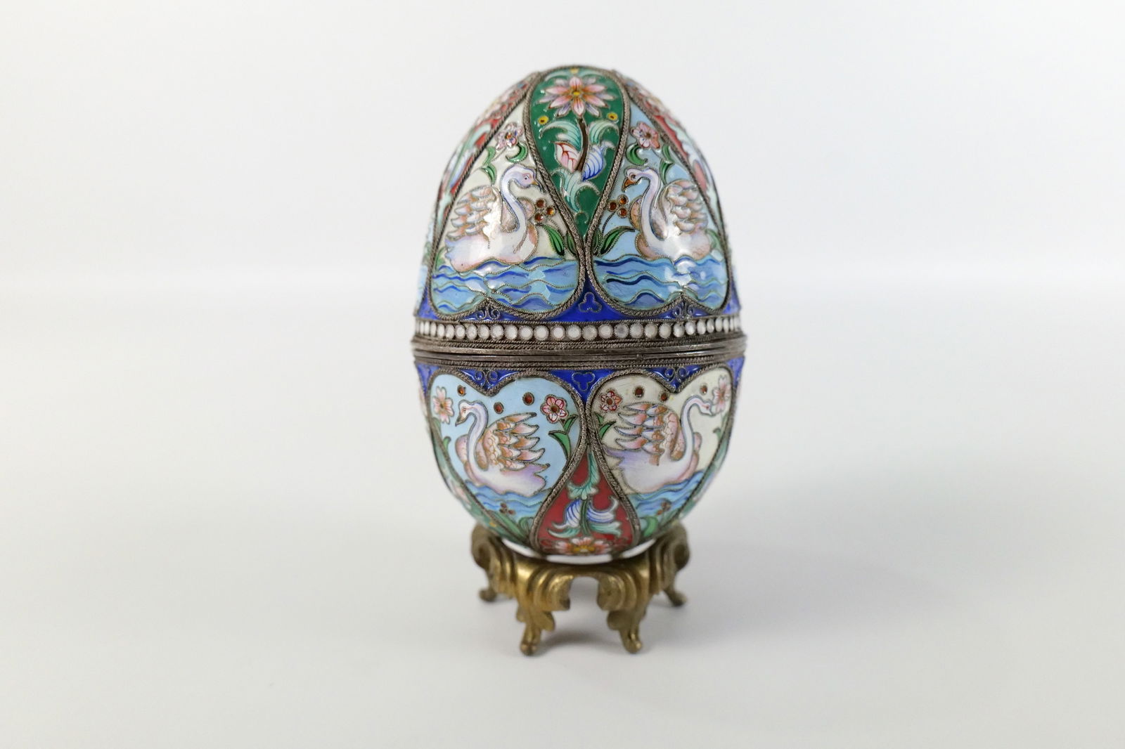 Russian Silver and Enamel Faberge Style Decorative Egg Box: Russian Silver and Enamel Faberge Style Decorative Egg Box. Swan and Flower Decoration. Unmarked. Comes with Stand - Not original to egg. Measures 5" tall x 3" diameter. All invoices must be paid with