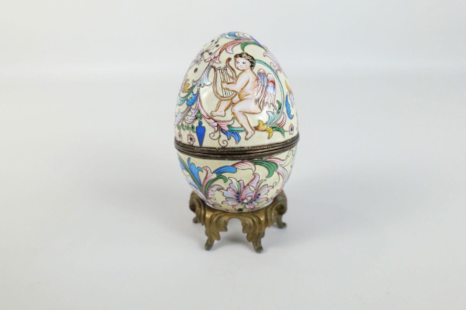Russian Silver and Enamel Faberge Style Decorative Egg Box: Russian Silver and Enamel Faberge Style Decorative Egg Box. Cherub Playing Harp and Flower Decoration. Unmarked. Has gold wash on the inside. Comes with Stand - Not original to egg. Measures 3.25" tal