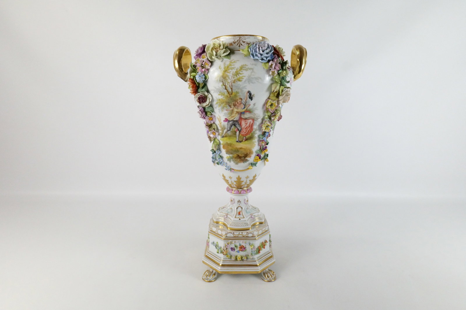 19th Century German Double Handled Pedestal Urn: 19th Century German Double Handled Pedestal Urn. Hand Painted depicting a man and woman dancing. Does have some missing flower petals. Missing Lid. Marked Germany with Cross Sword. Measures 21" tall x
