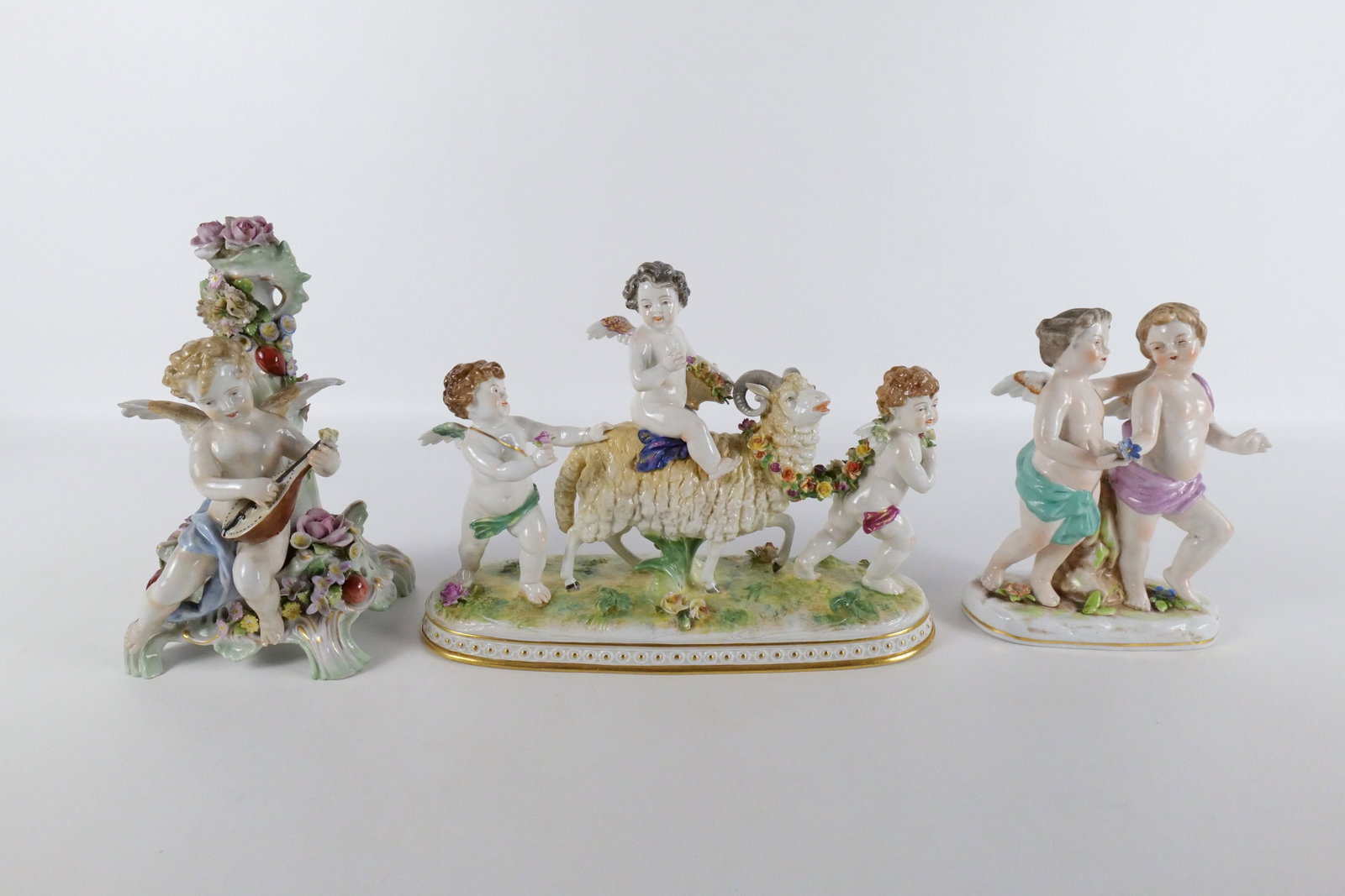 Lot of 3 Antique Hand Painted Porcelain Figurines: Lot of 3 Antique Hand Painted Porcelain Figurines including Figural Grouping of Putti's with a Goat - AS-IS - Arm has been repaired, missing basket handle, Some chips to flowers - Volkstedt Mark on ba