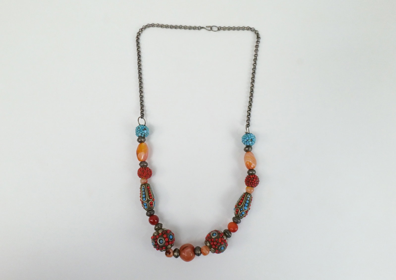 Bohemian Carnealian Bead Necklace: Bohemian Carnealian Bead Necklace. The lot includes a 23.5'' long necklace featuring a variety of carnealian beads, silver tone beads set with faux turquoise and faux coral balls set in a resin like m