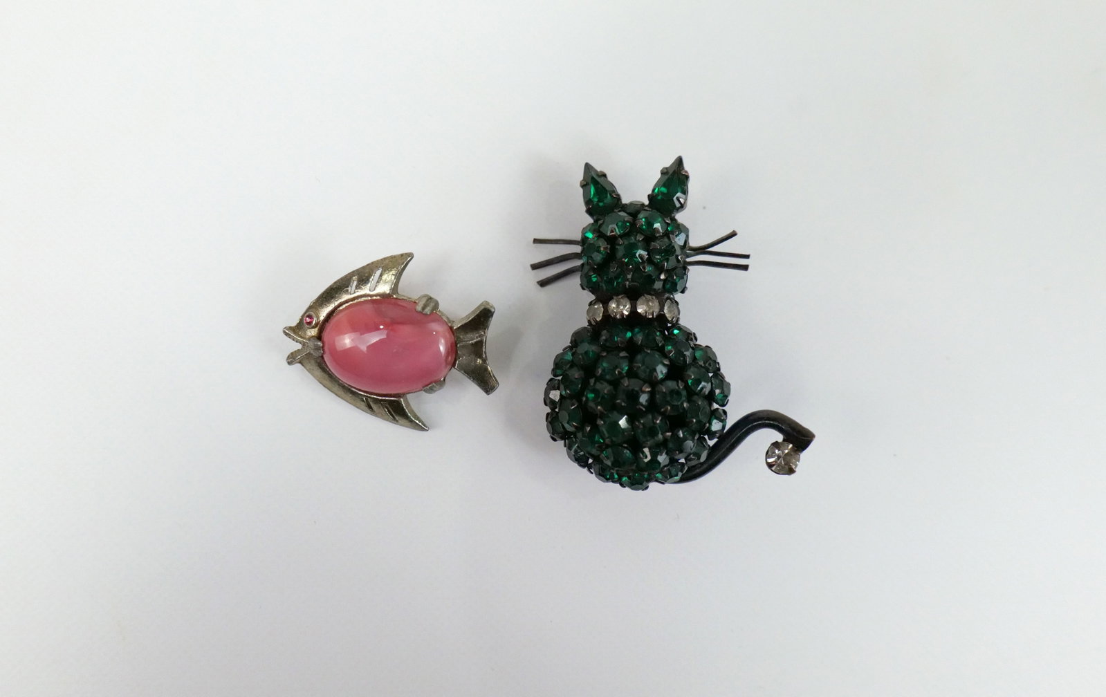 Pair of Vintage Cat and Fish Brooches: Pair of Vintage Cat and Fish Brooches. The lot includes 2 vintage brooches featuring a 1 3/4'' x 1.5'' green rhinestone cat brooch by Werner. Marked Werner, used. Also included is a 1'' x 1'' vintage 