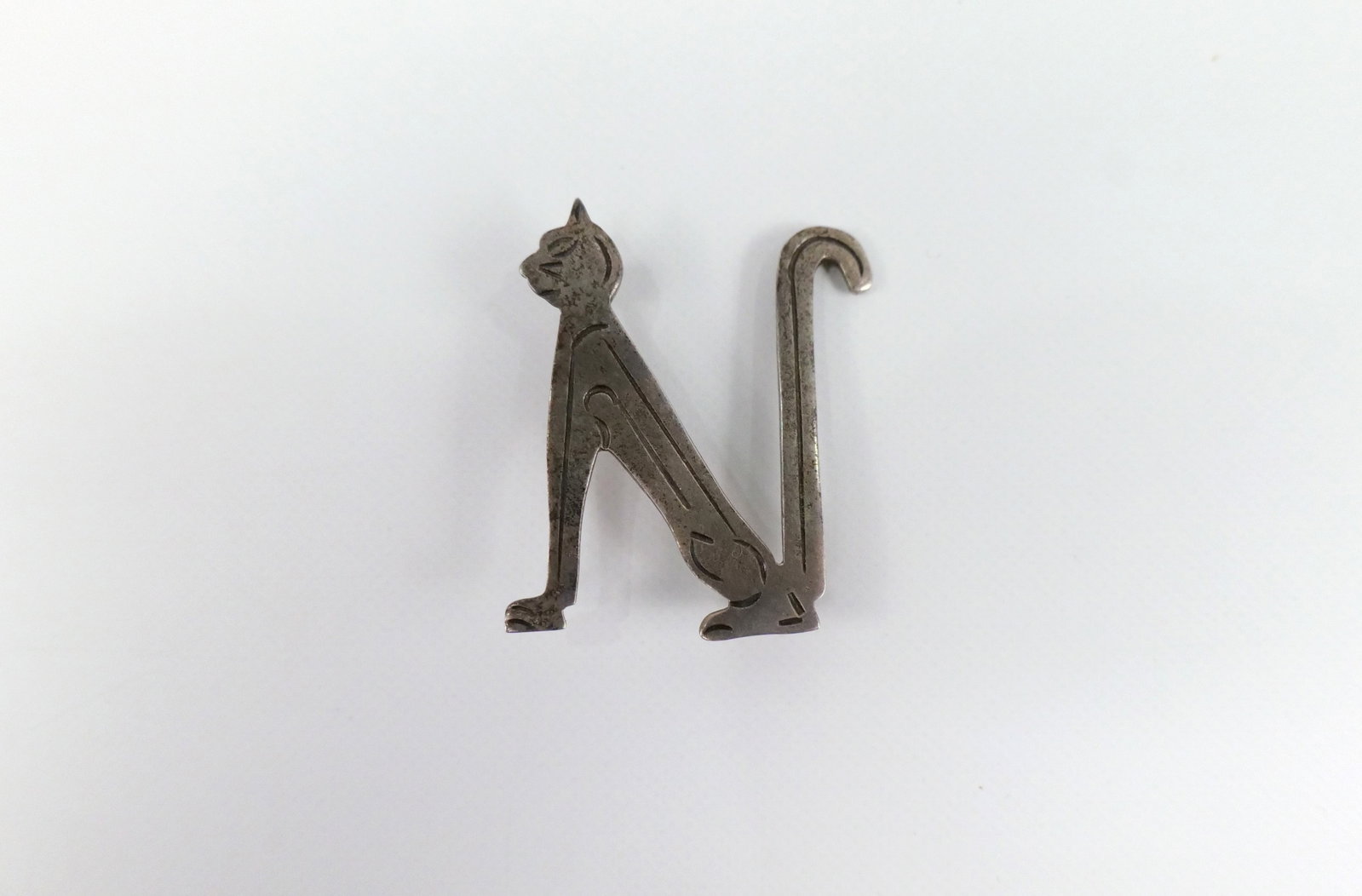 Mexican Sterling Cat Shaped Letter Brooch: Mexican Sterling Cat Shaped Letter Brooch. The lot includes 1 vintage Mexican made sterling cat shaped letter "N" brooch measuring 1.5'' x 1.23''. Marked Mexico 925, used. All invoices must be paid wi